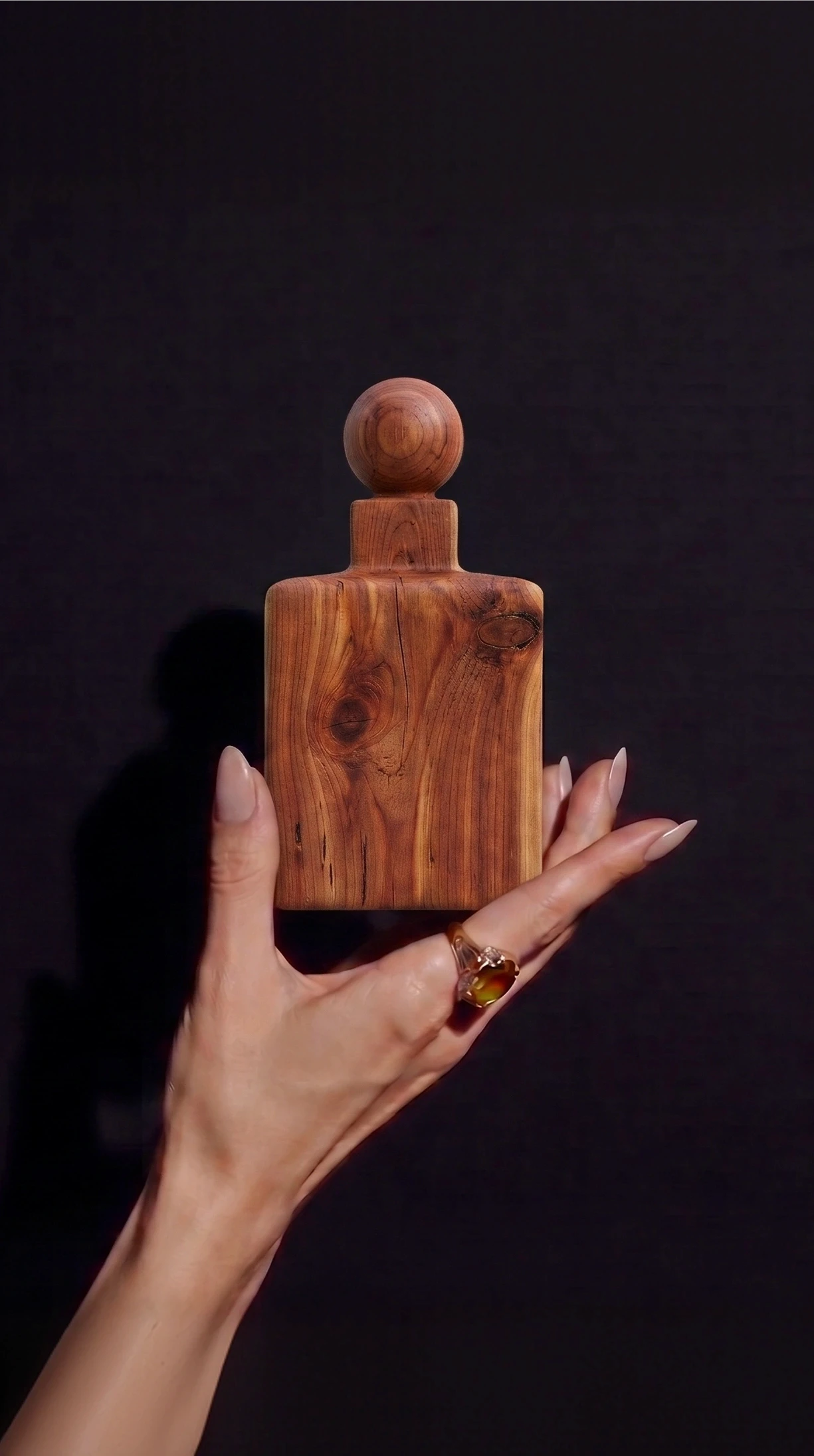 mano cogiendo frasco perfume madera