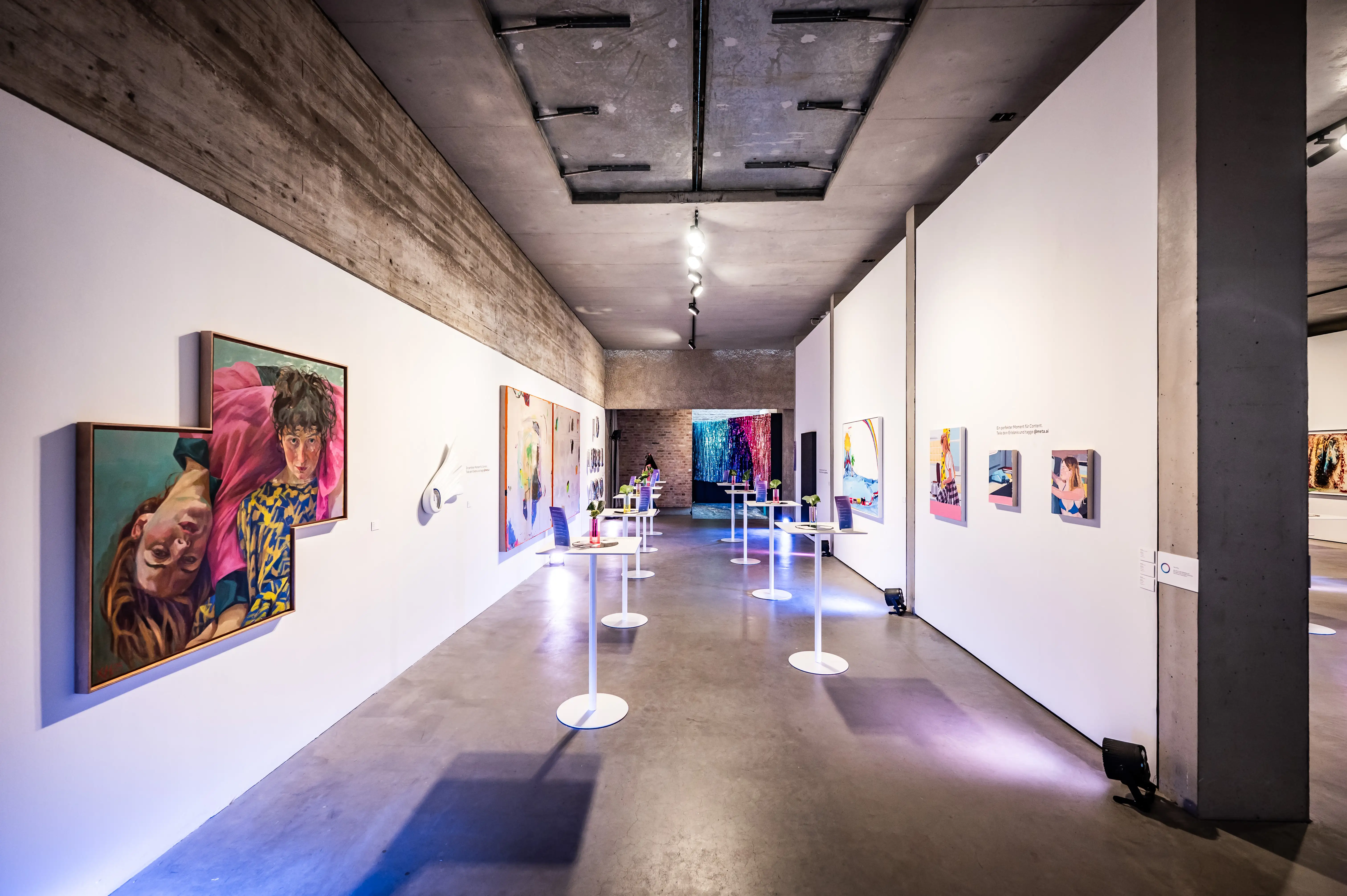 Gallery corridor with colourful paintings and illuminated high tables at the Meta Summit.
