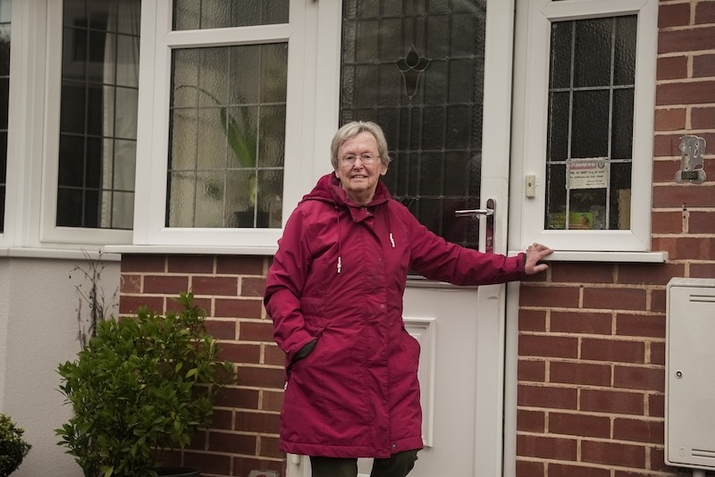 Woman smiling outside the front of her home.
