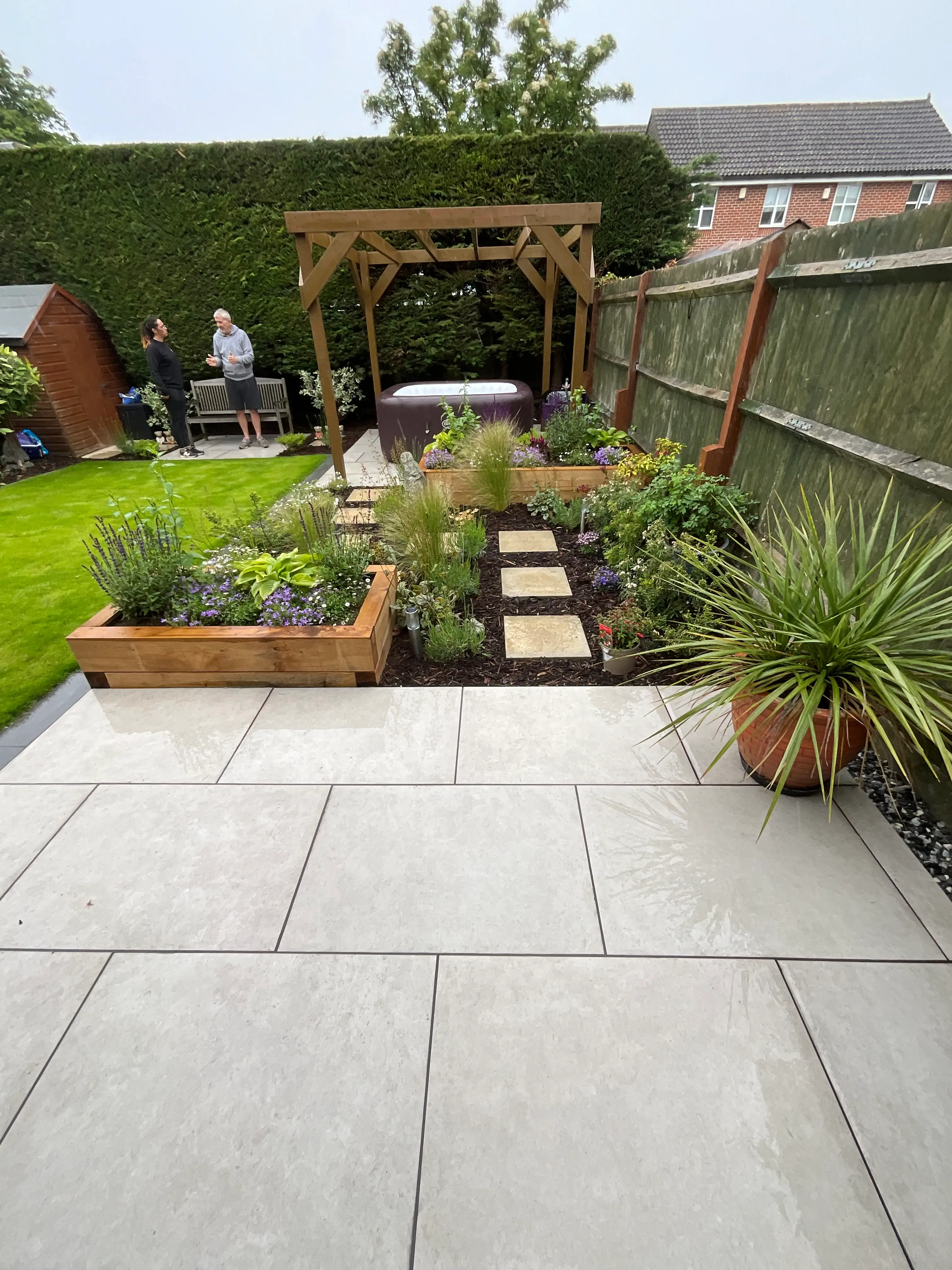 A well-maintained garden path with stone slabs, surrounded by plants and leading to a wooden gazebo.