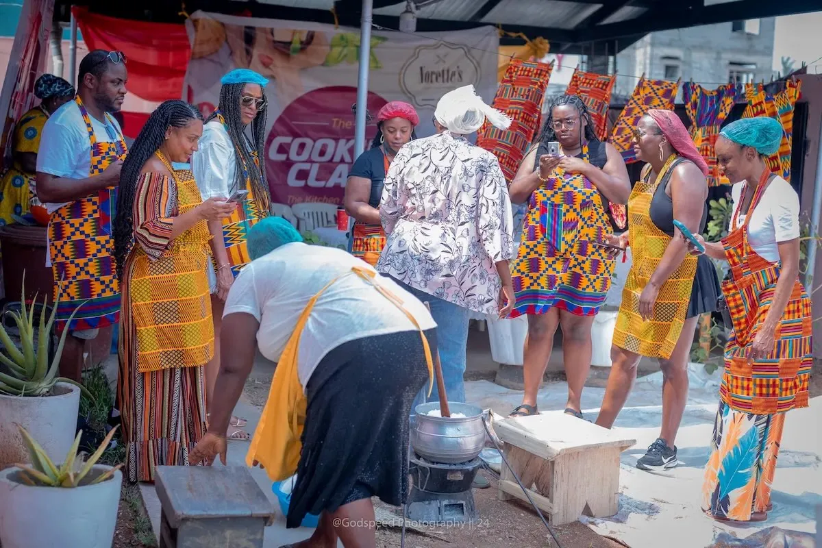 A group of travelers in kente-print aprons.