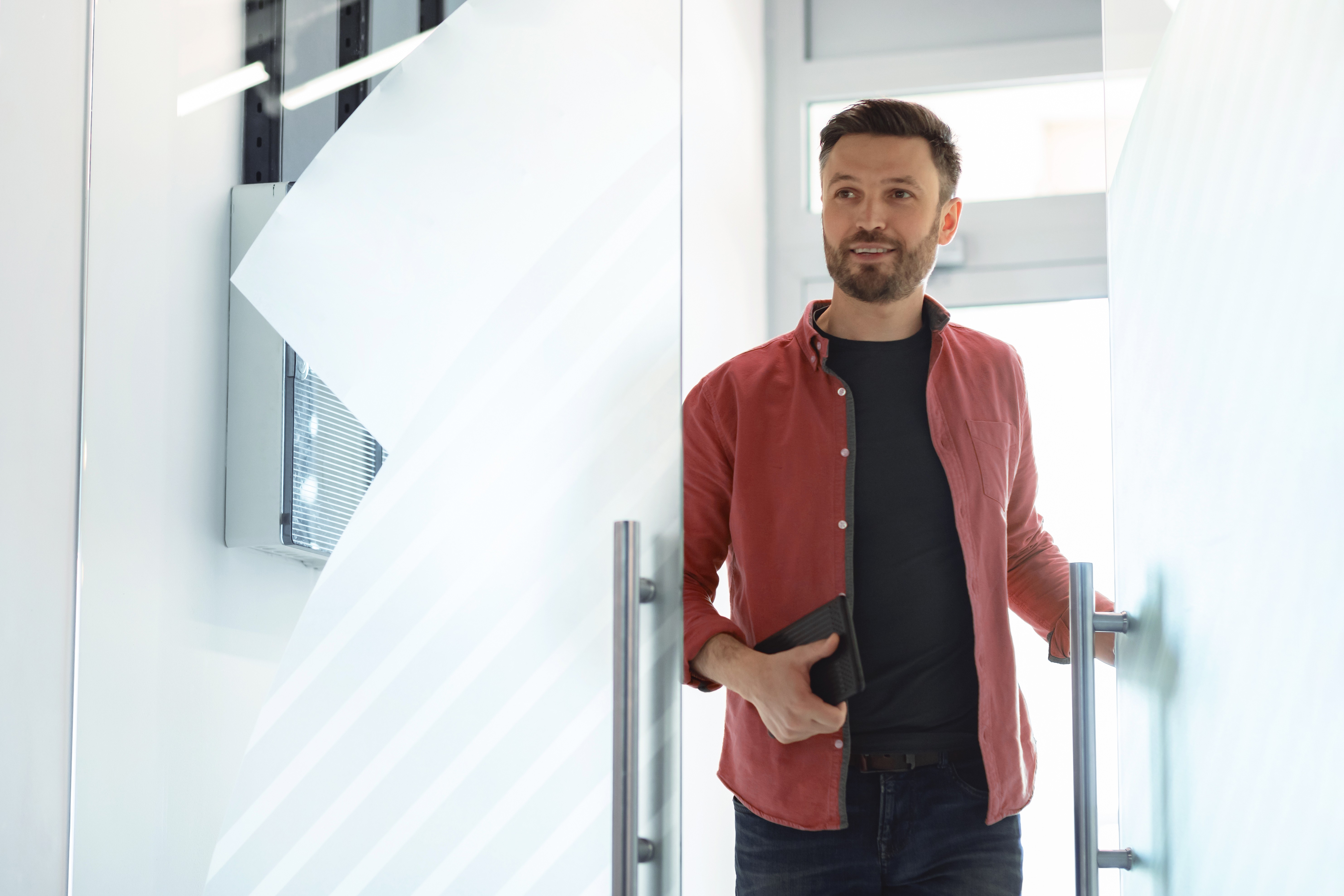 Confident business owner walking through glass door having successfully exited a bridging loan