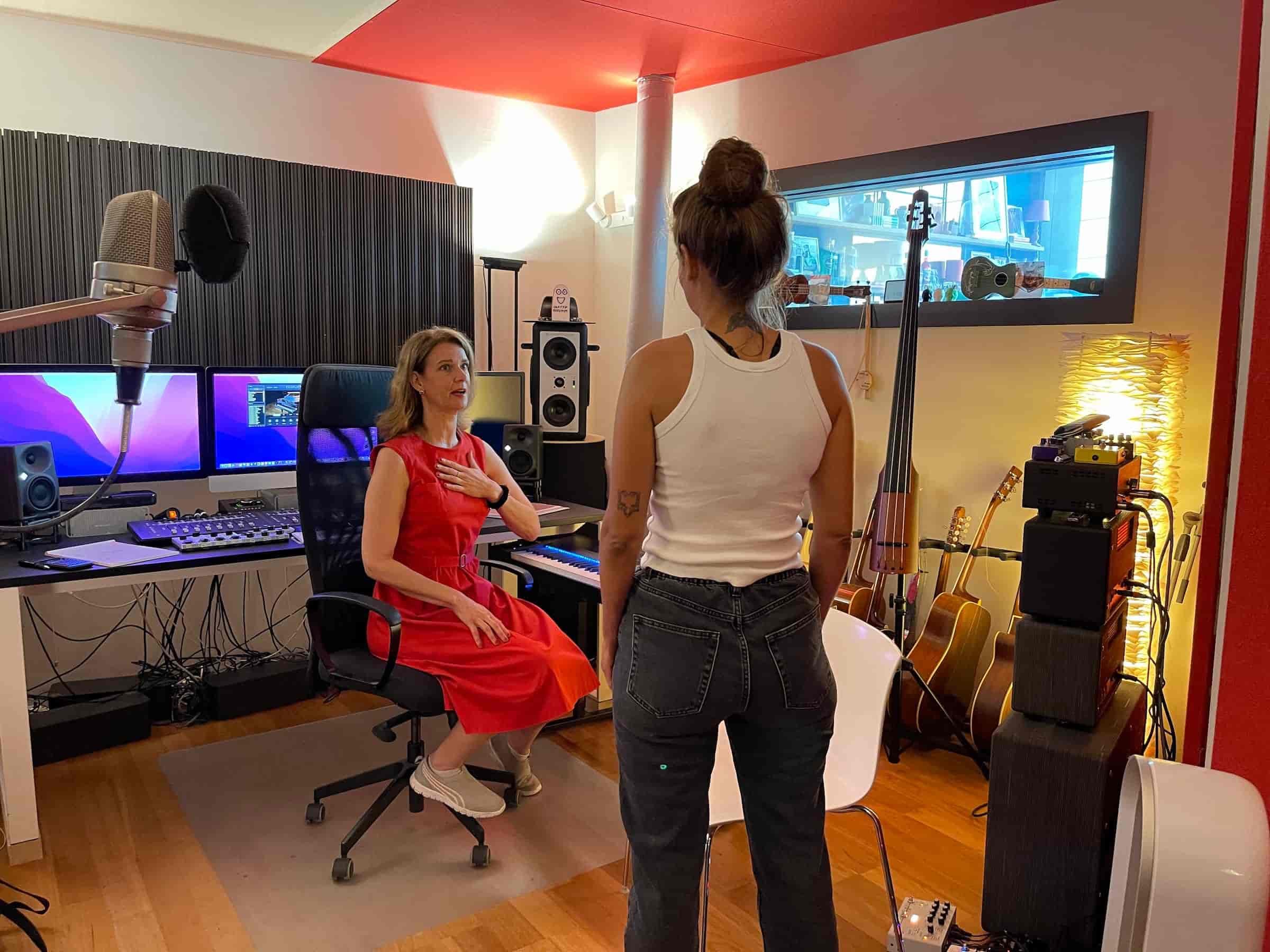 Exklusives VIP Gesangscoaching im Tonstudio: Vocal Coach Danielle Zuber arbeitet intensiv 1:1 mit einer Sängerin. Im Hintergrund ist professionelles Studio-Equipment wie Mikrofone, Monitore und Instrumente zu sehen.
