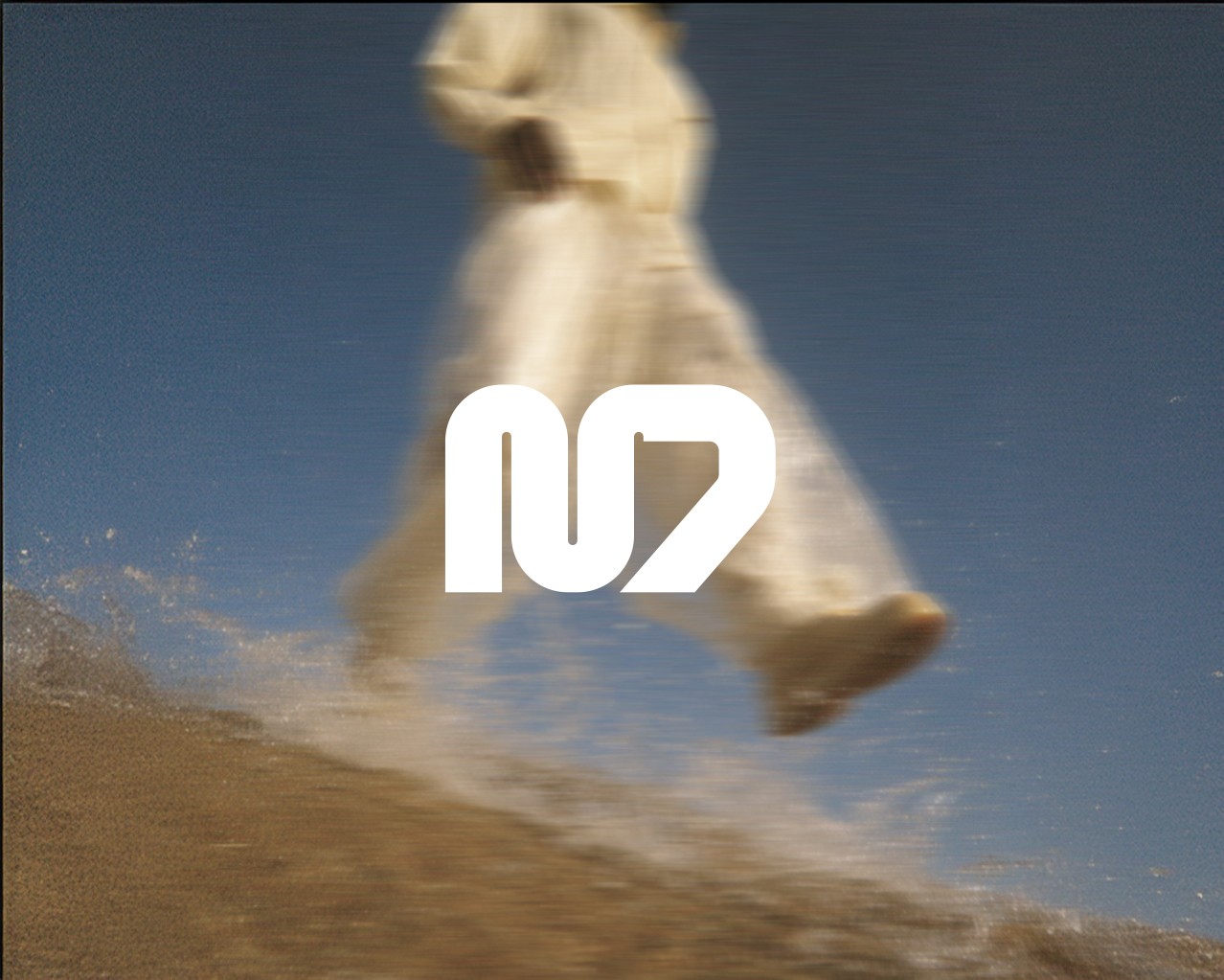 Leicht verwaschenes Bild eines Mannes im Regenmantel mit weißem Logo mittig auf dem Bild platziert.