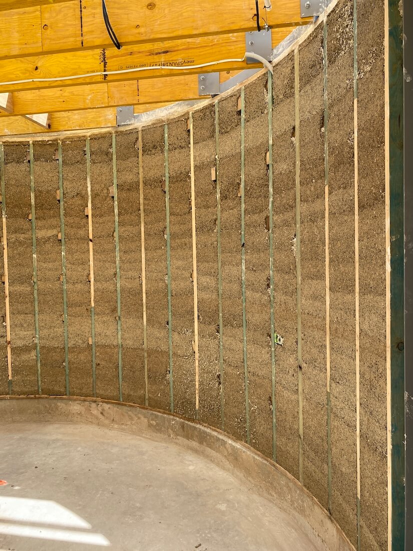 The photo shows installing hempcrete blocks on the wall