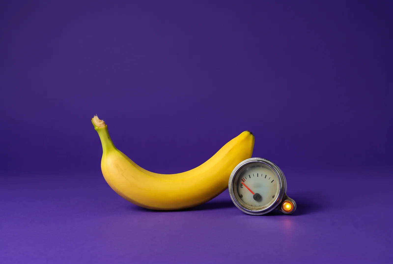 A banana beside a fuel gauge on empty and a glowing warning light, the warning signs and HALT check in a porn relapse prevention plan