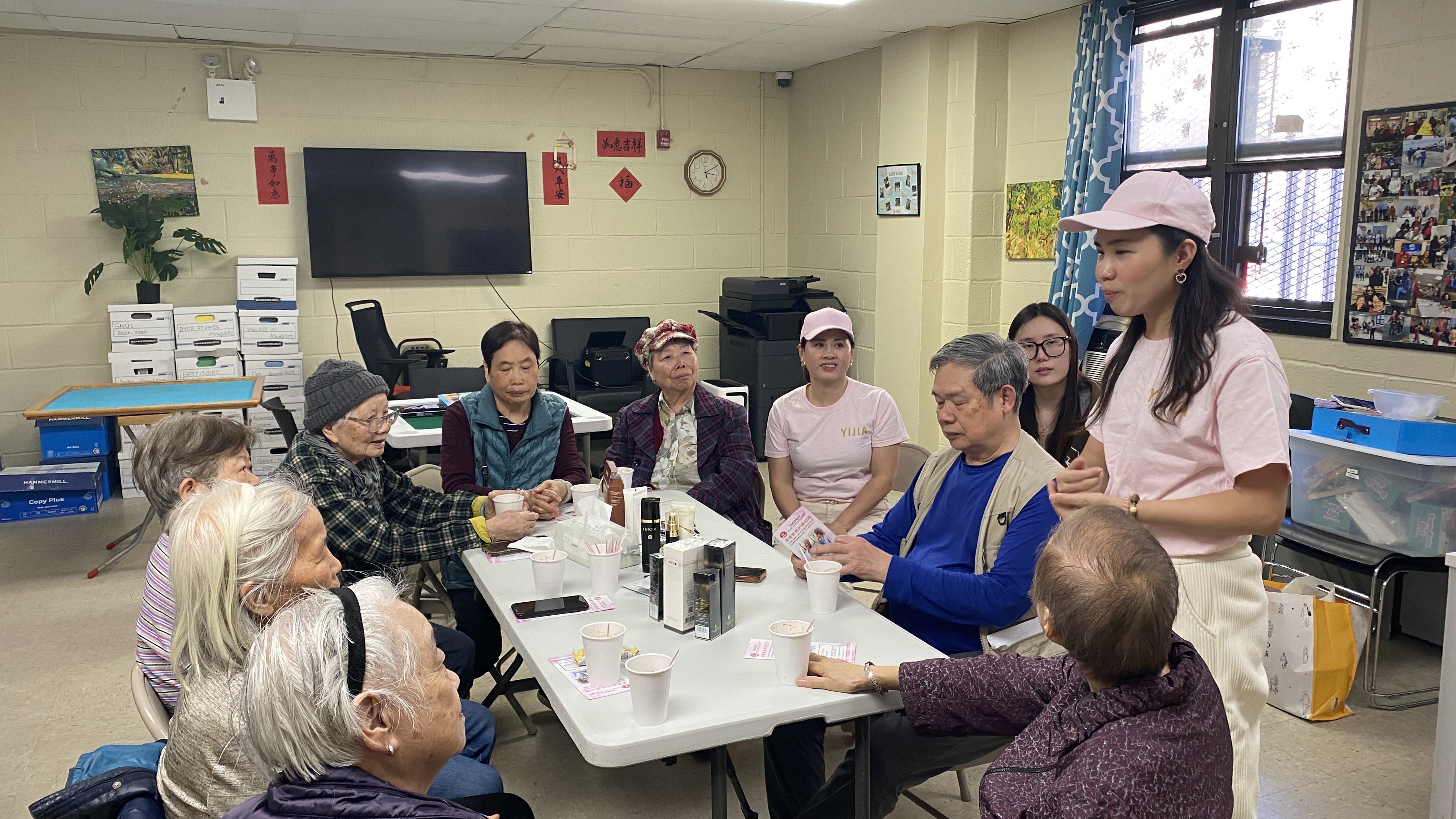 A volunteer leads Senior participants in a skincare routine demonstration.