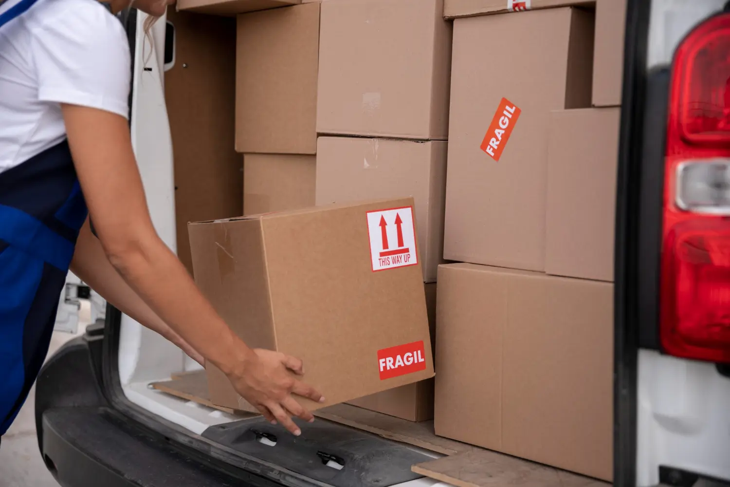 Warehouse worker loading fragile-labeled boxes into a delivery van