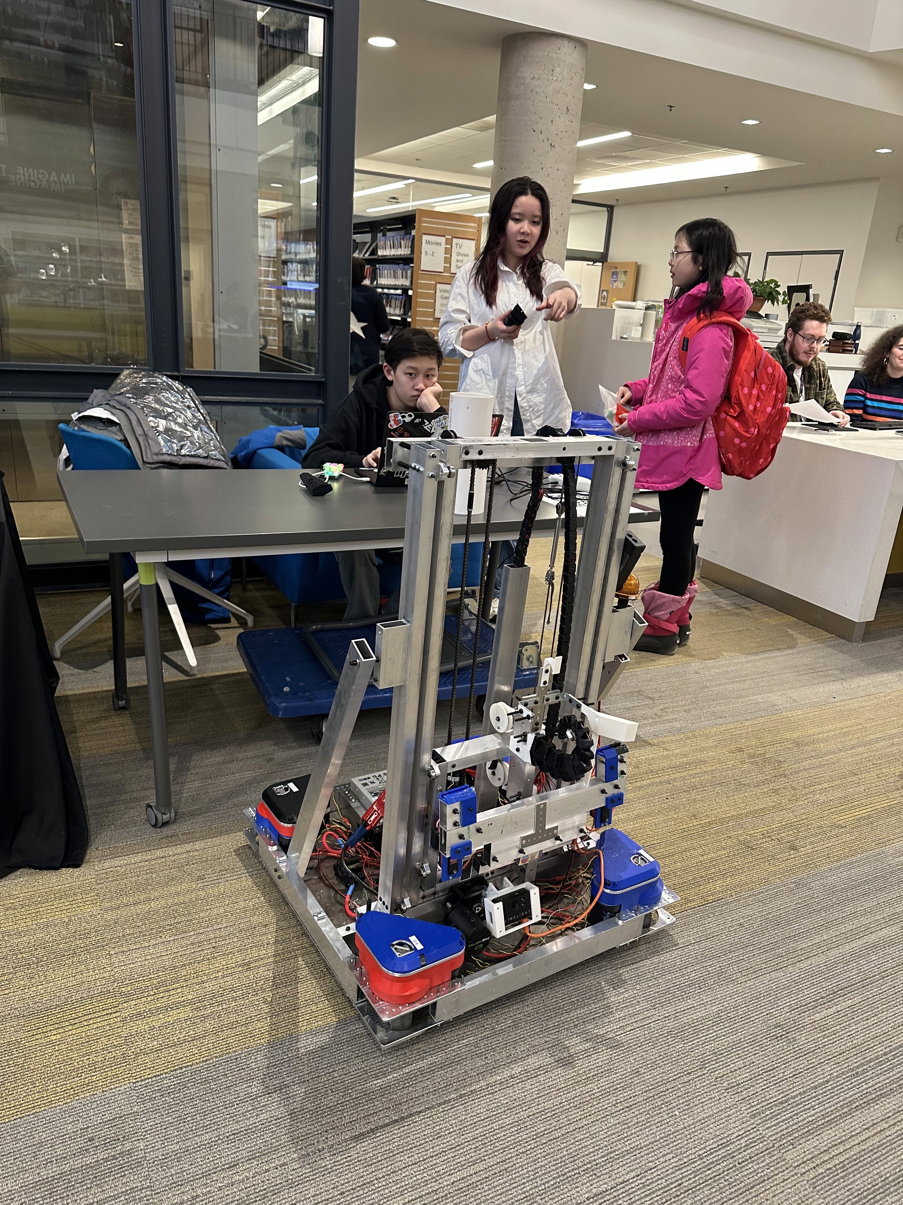 Co-captain Queena Lin Explains FRC and the robot to a high school student.