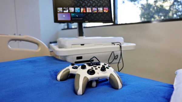 Two Turtle Beach Xbox controllers on a hospital bed in front of a Gamers Outreach Kart.