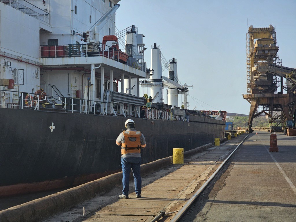 Marine surveyor alongside a bulk carrier at Itaqui Port terminal during draft survey attendance prior to cargo operations.