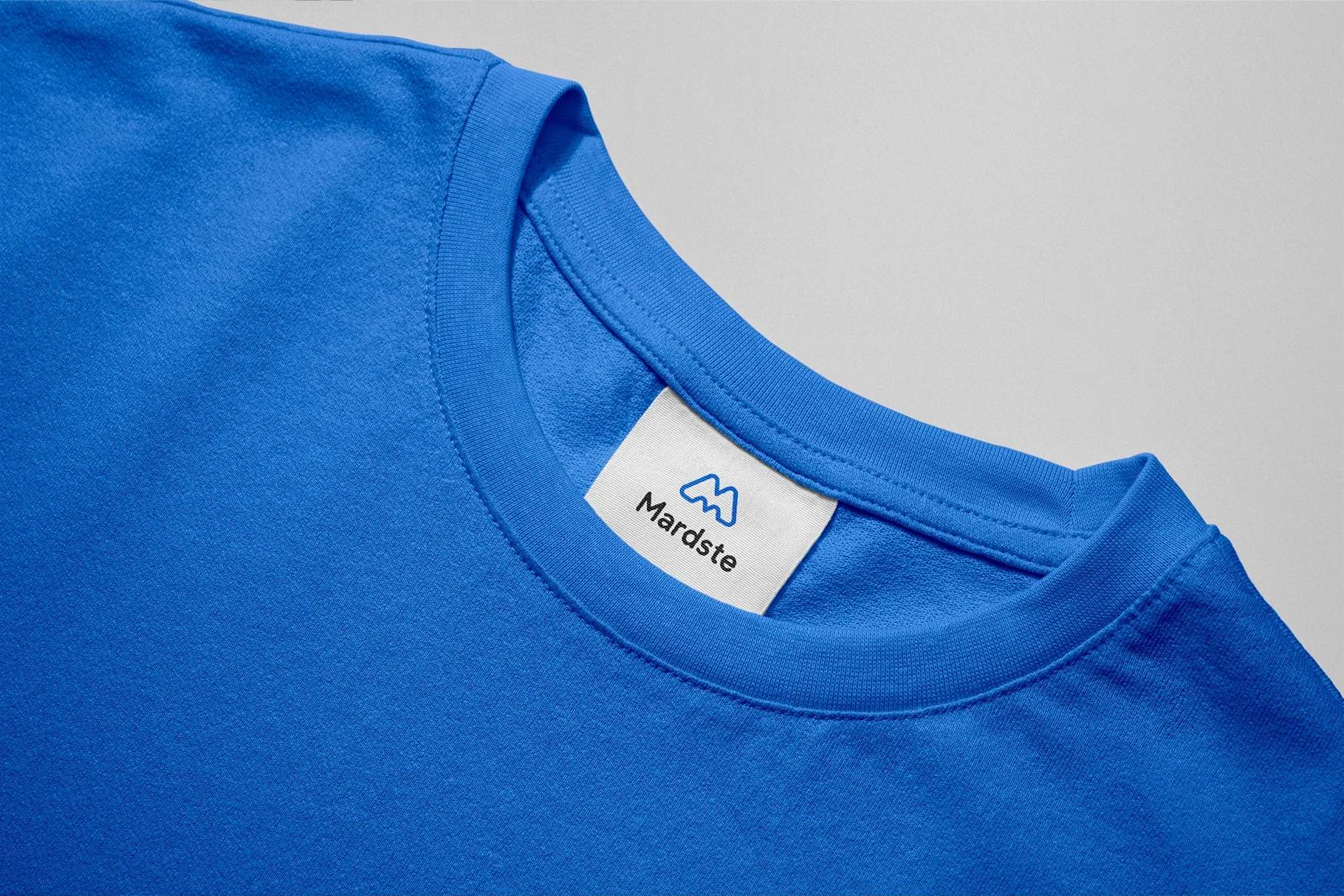 Close-up of a clothing label mockup on a vibrant blue t-shirt.