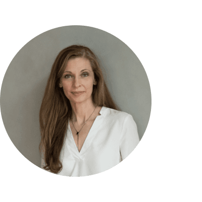 Editorial portrait of a young man with wavy hair in a knit sweater, looking over his shoulder in soft light.
