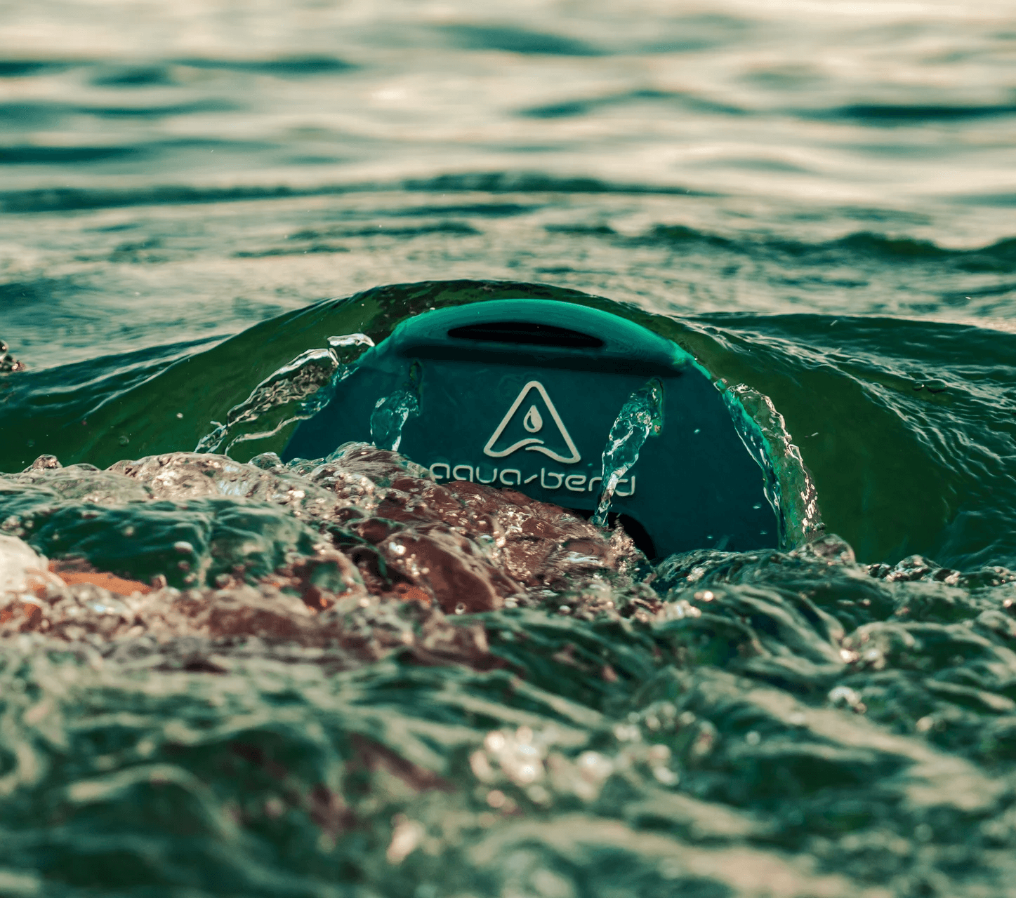 Close-up of hand gripping Aqua-Bend disc during chest press, water rippling over the disc from resistance