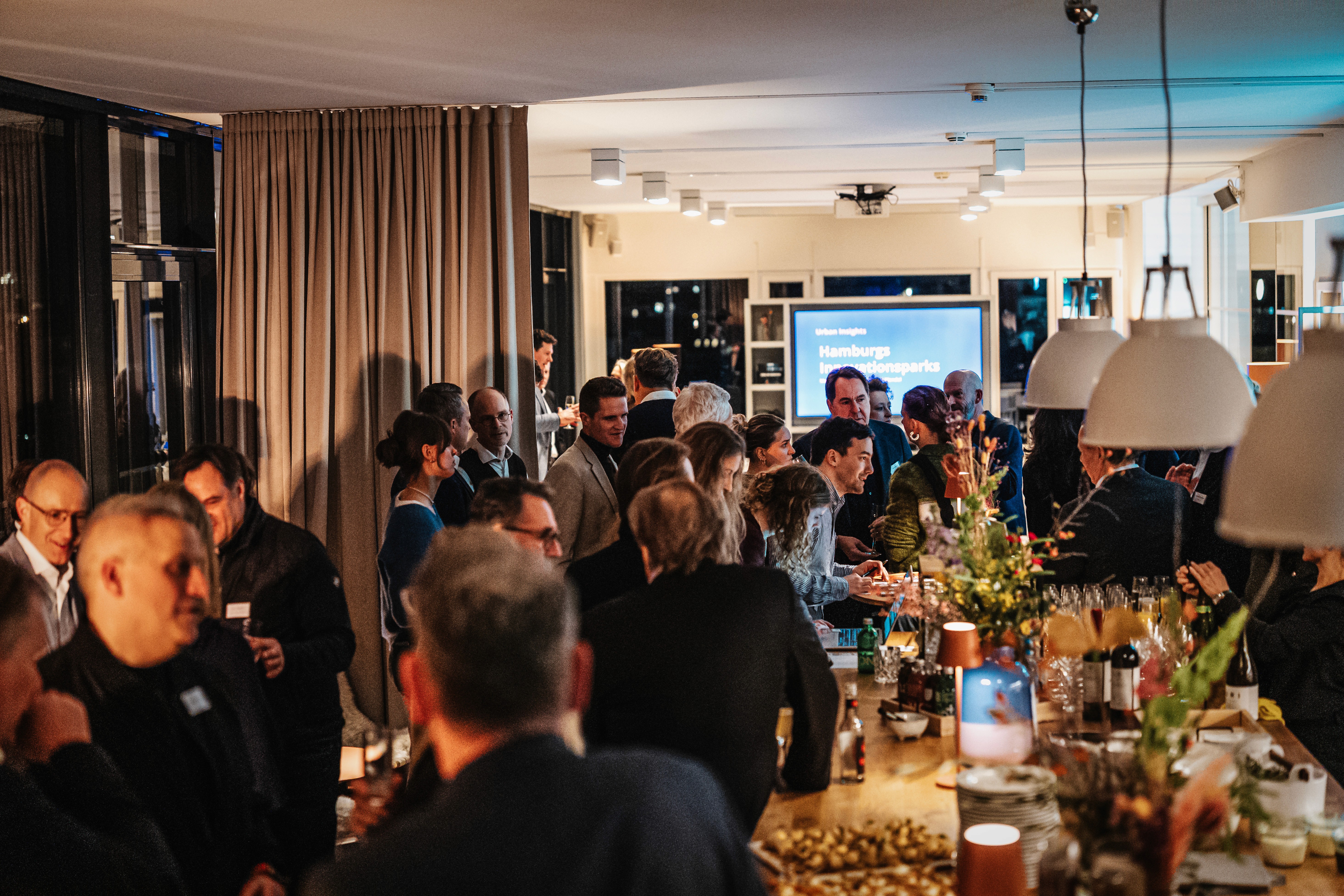 People crossing a busy street with cars and buildings.