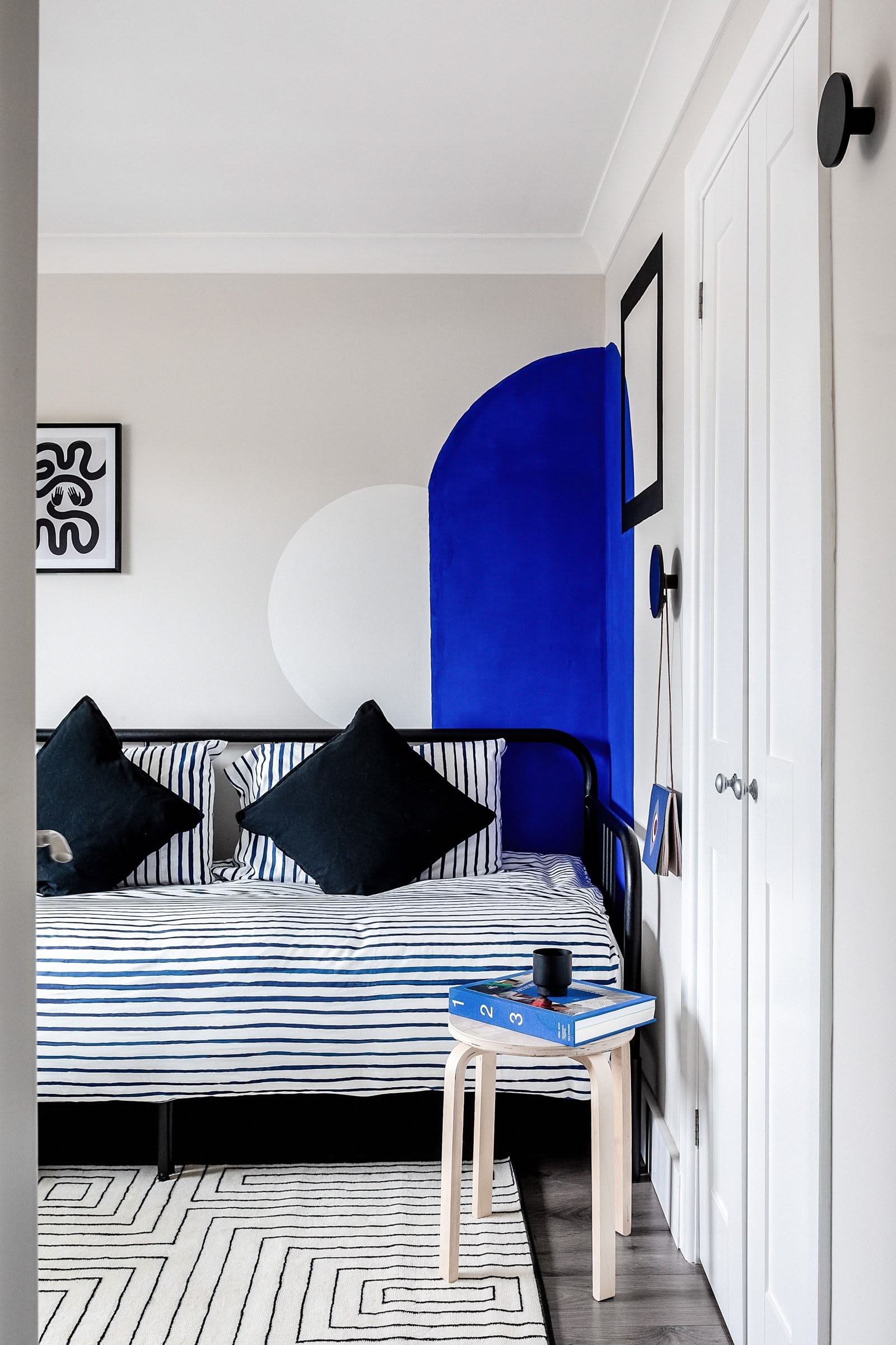 Interior design studio Atelier Akuko creates a bespoke geometric electric blue mural in a kids' bedroom of a London new build for a refugee family home.