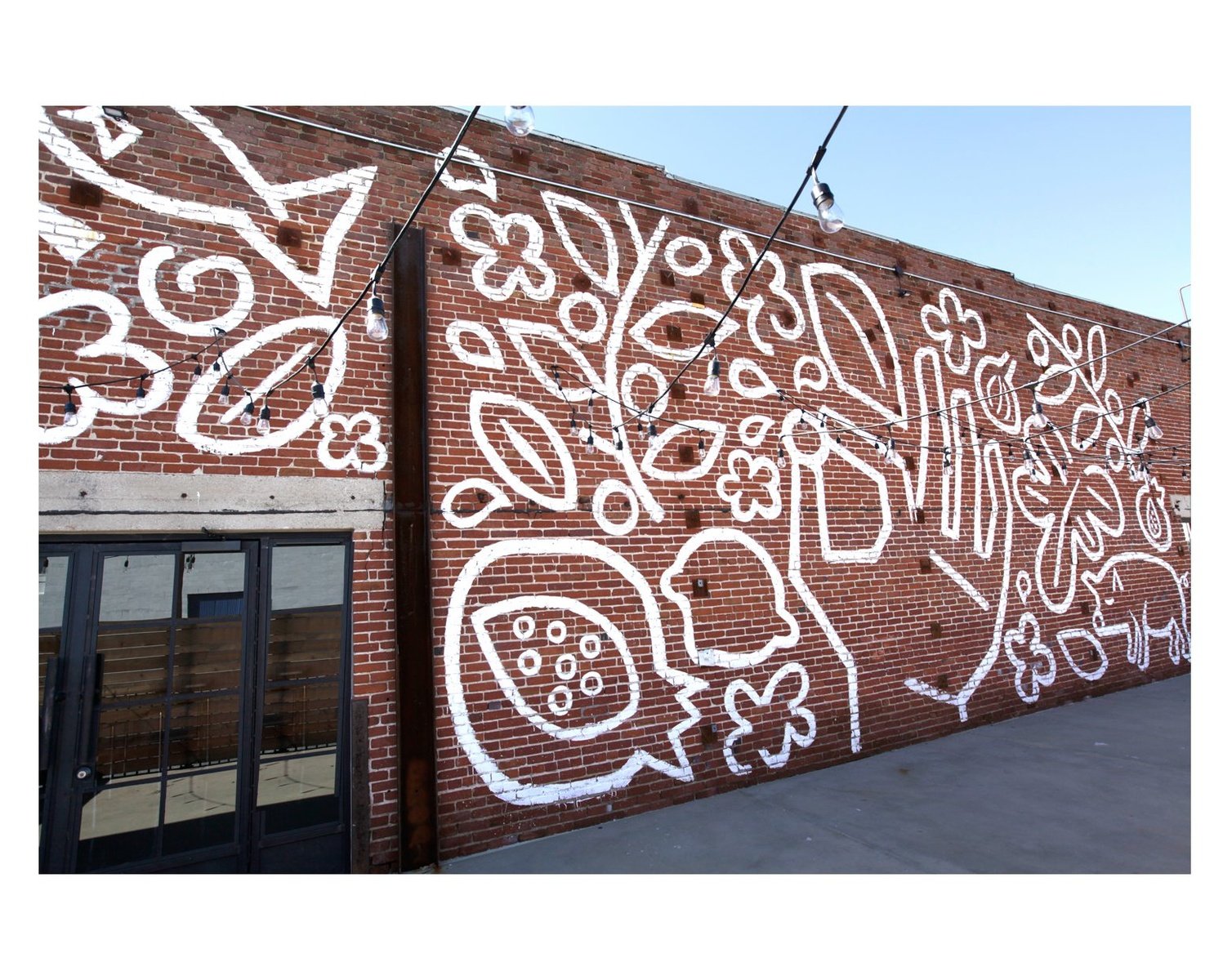 White linework food mural across Crafted Kitchen’s brick exterior.
