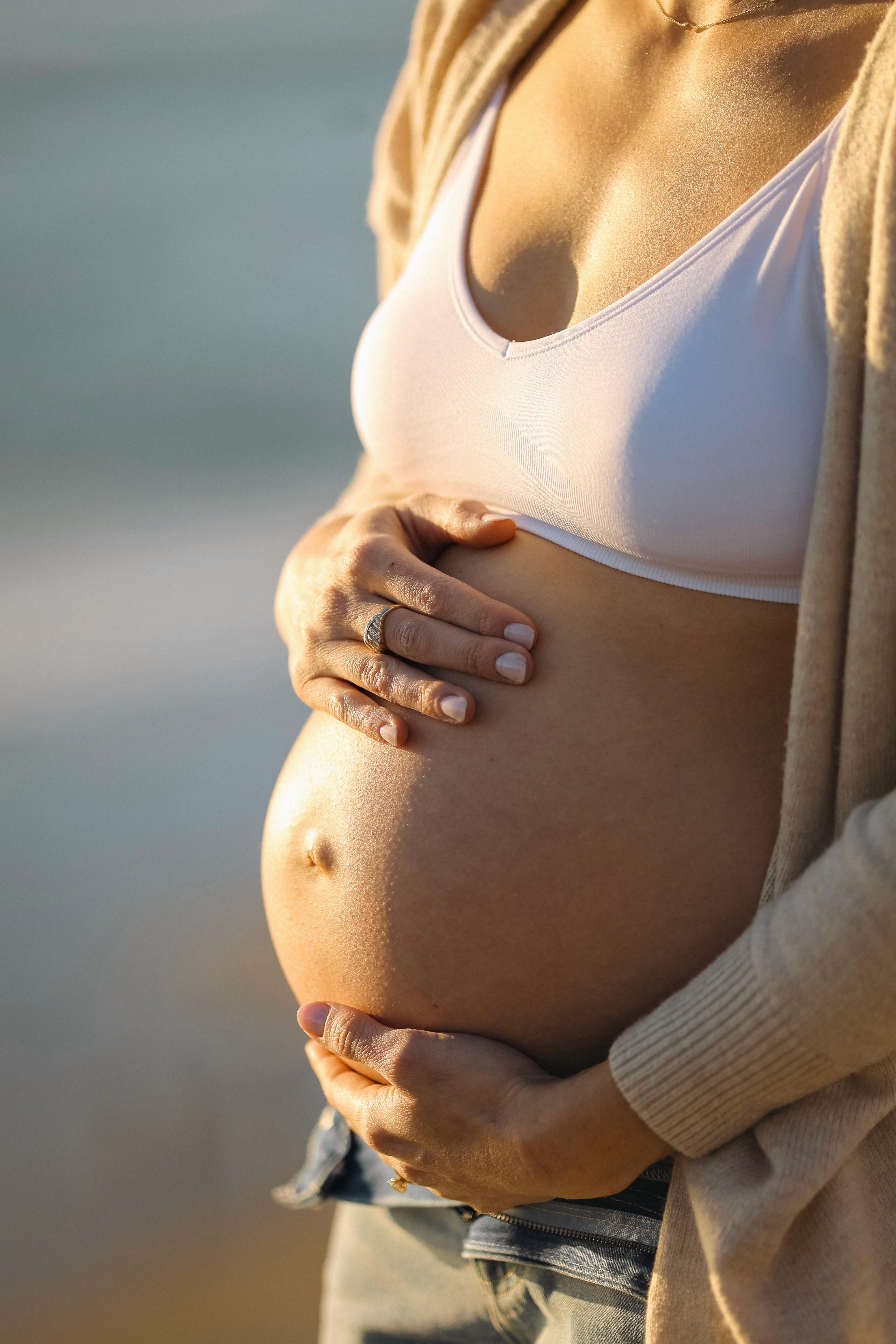 Close-up of pregnant belly with warm sunset light during a maternity session.