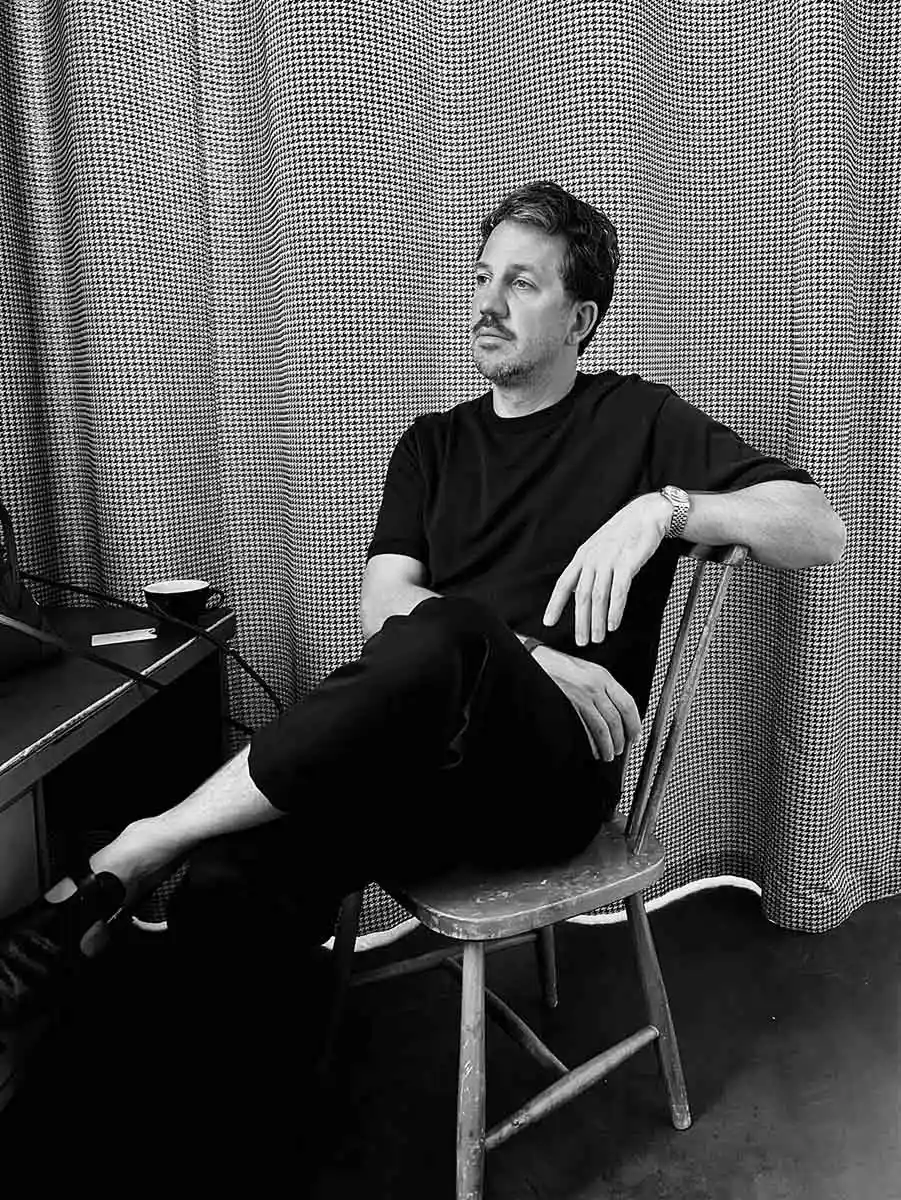Black-and-white portrait of Michiel Spijkers seated in front of patterned curtains.