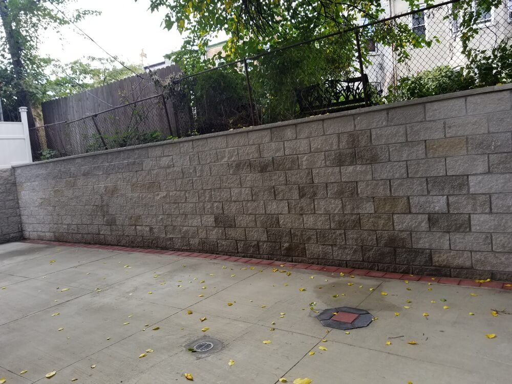 Professional retaining wall restoration with new thermal color face CMU block and blue stone cap by Jewel Construction Company in Brooklyn, NYC