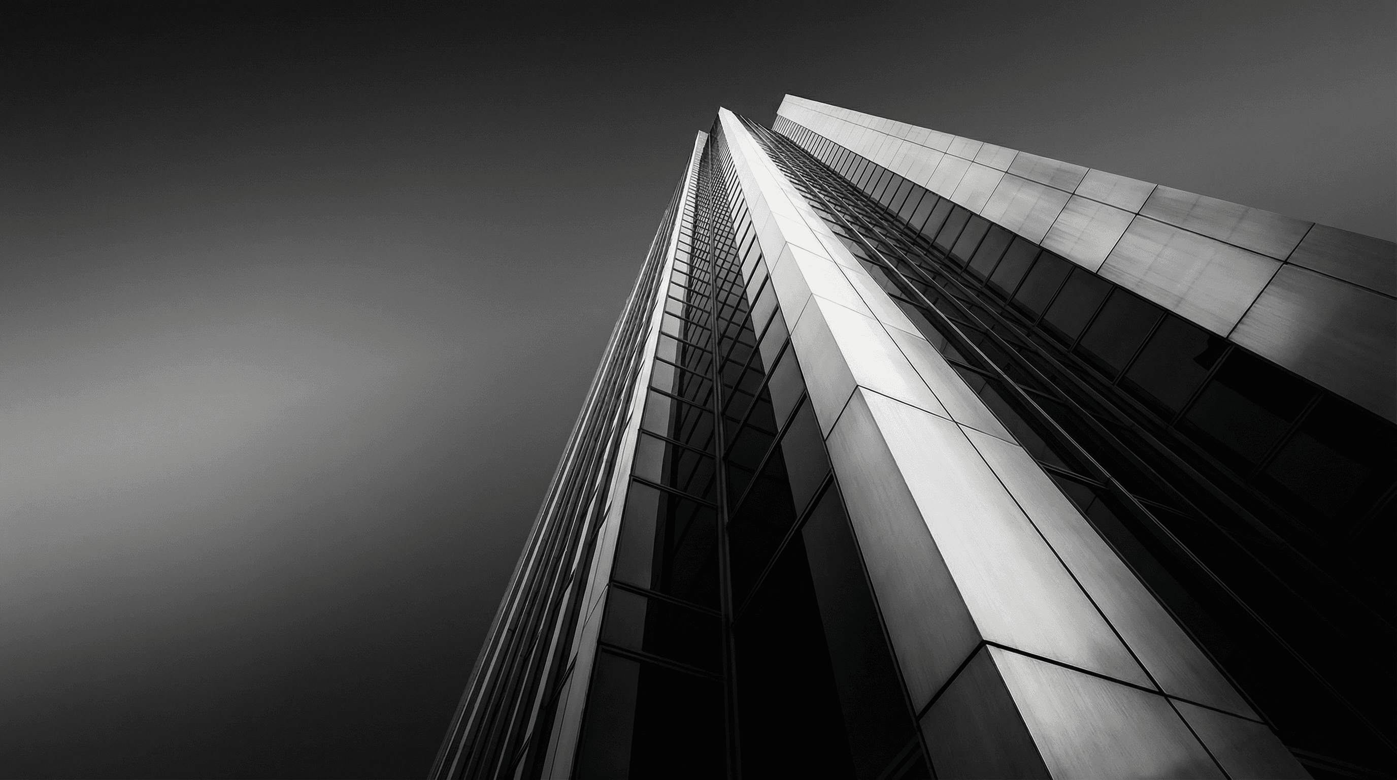 Smiling young man with short hair poses against a dark background, wearing a green button-up shirt.