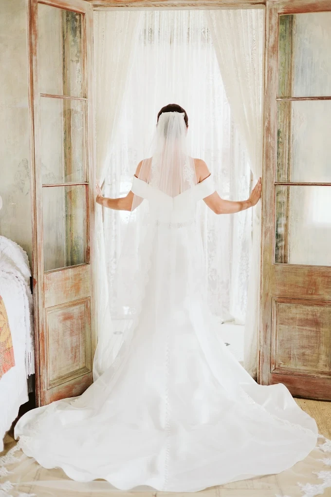 a woman standing in front of a row of wedding dresses