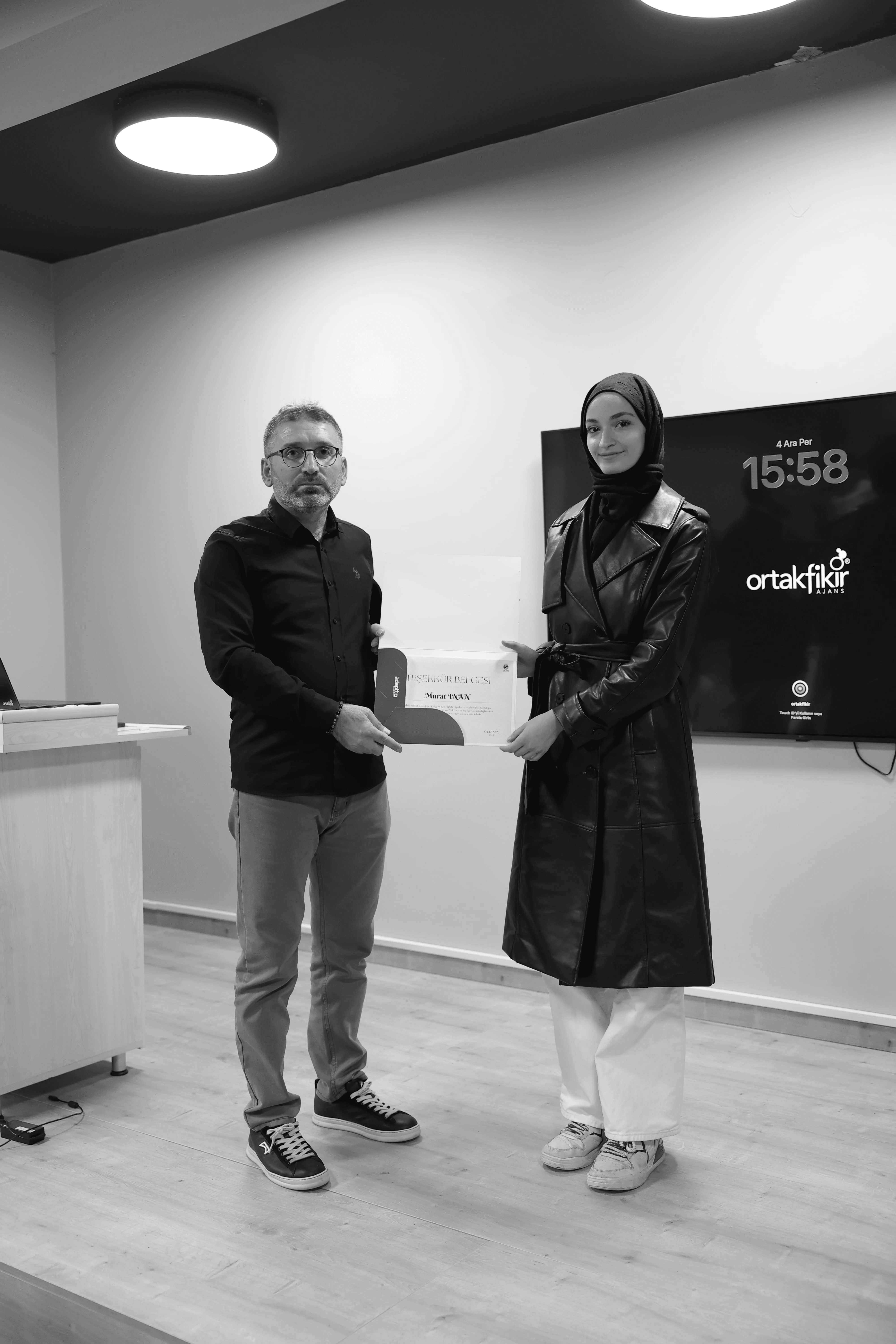 Four people engage in conversation in front of a wall with text, all smiling and interacting in a casual setting.