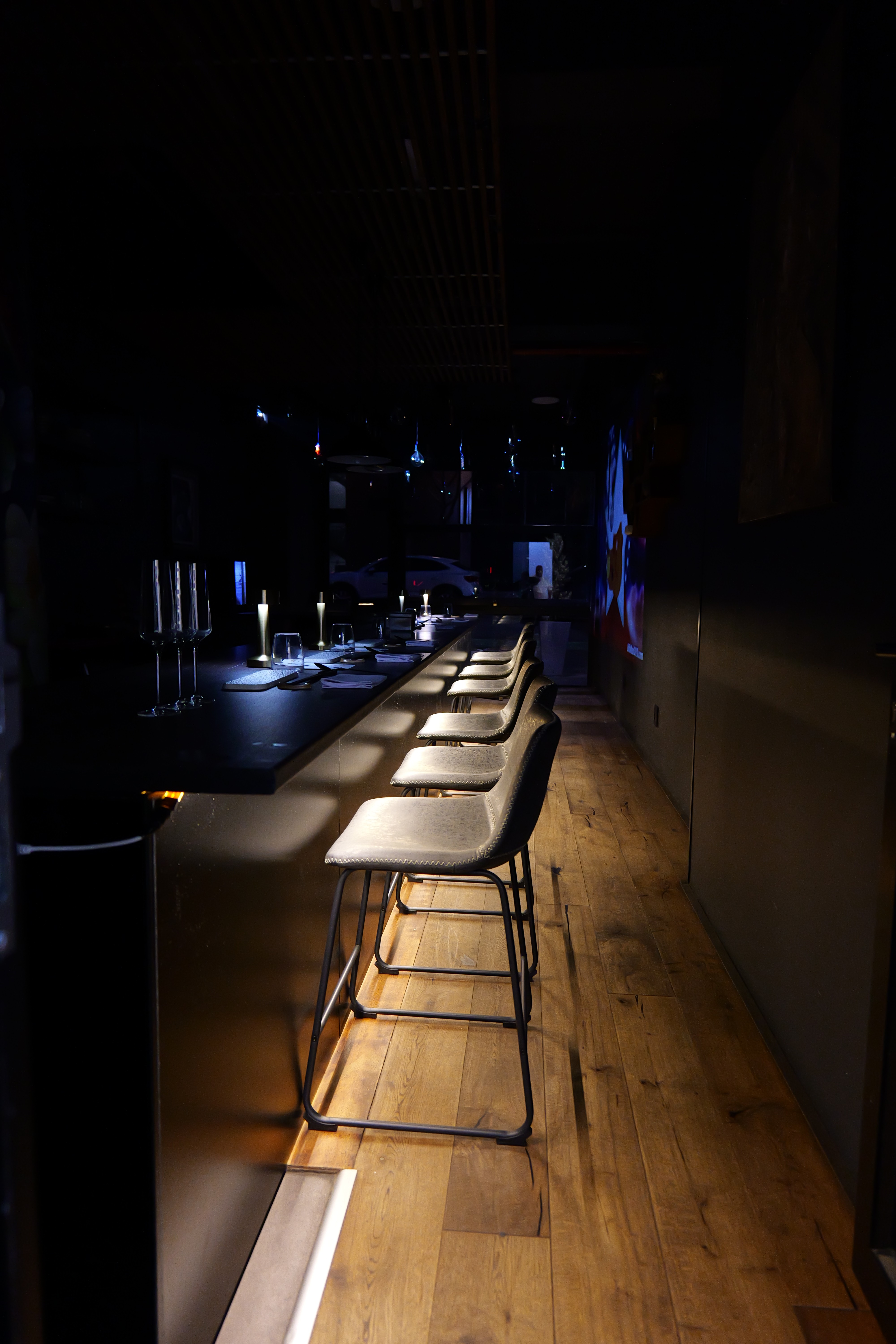 Cozy cafe corner with a round terrazzo table surrounded by wooden chairs, decorated with potted plants and a large mirror reflecting warm light.