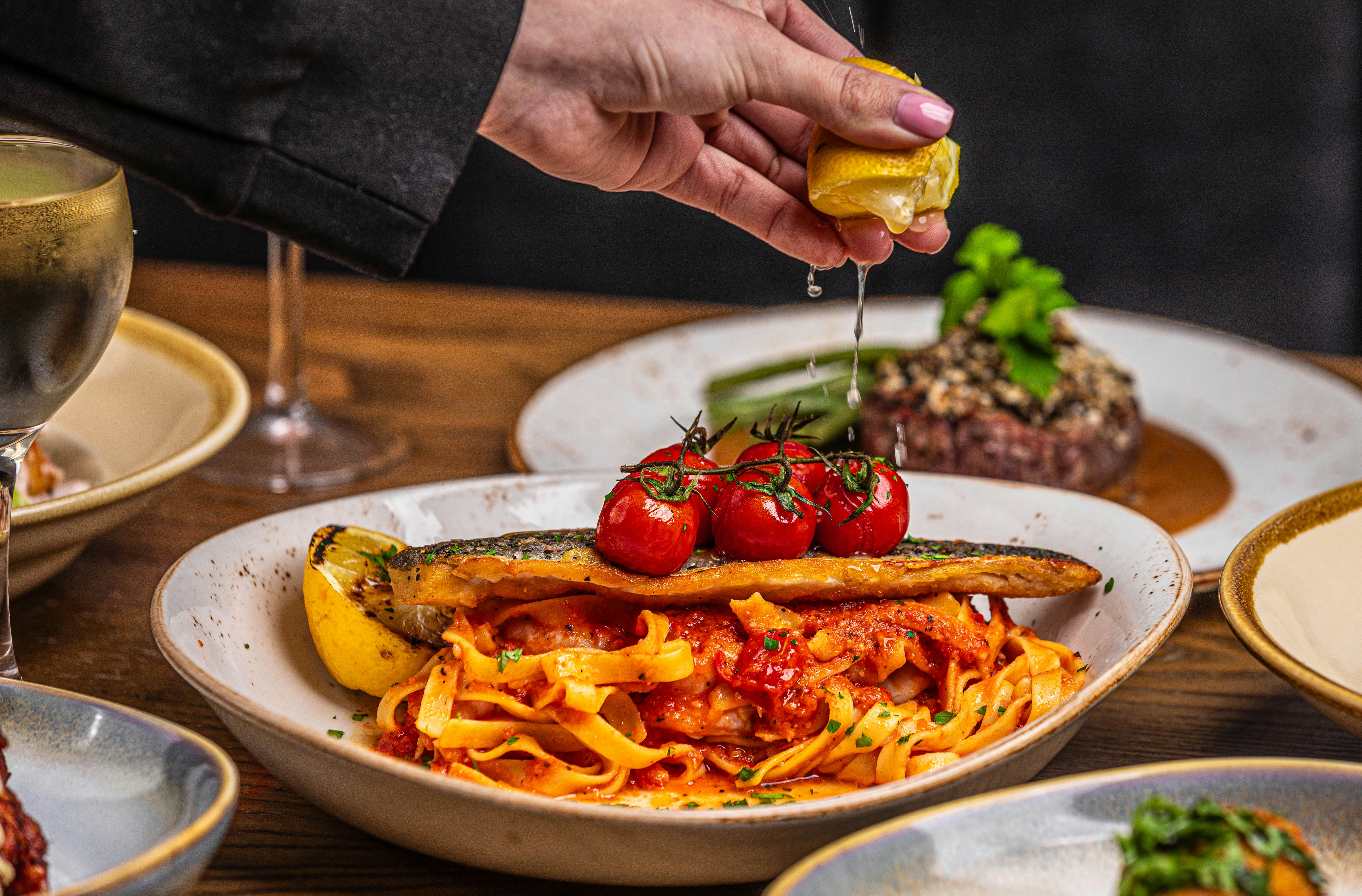 Tomato and lemon getting squeezed on a dish