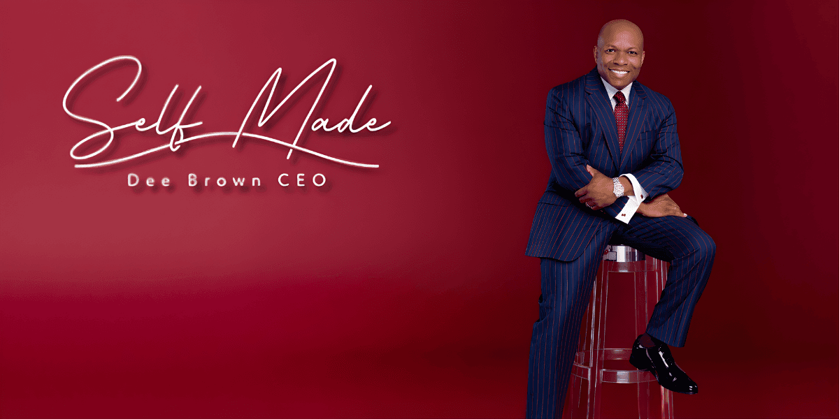 A man in a suit sits confidently on a chair, embodying resilience and ambition in his journey from poverty to success.