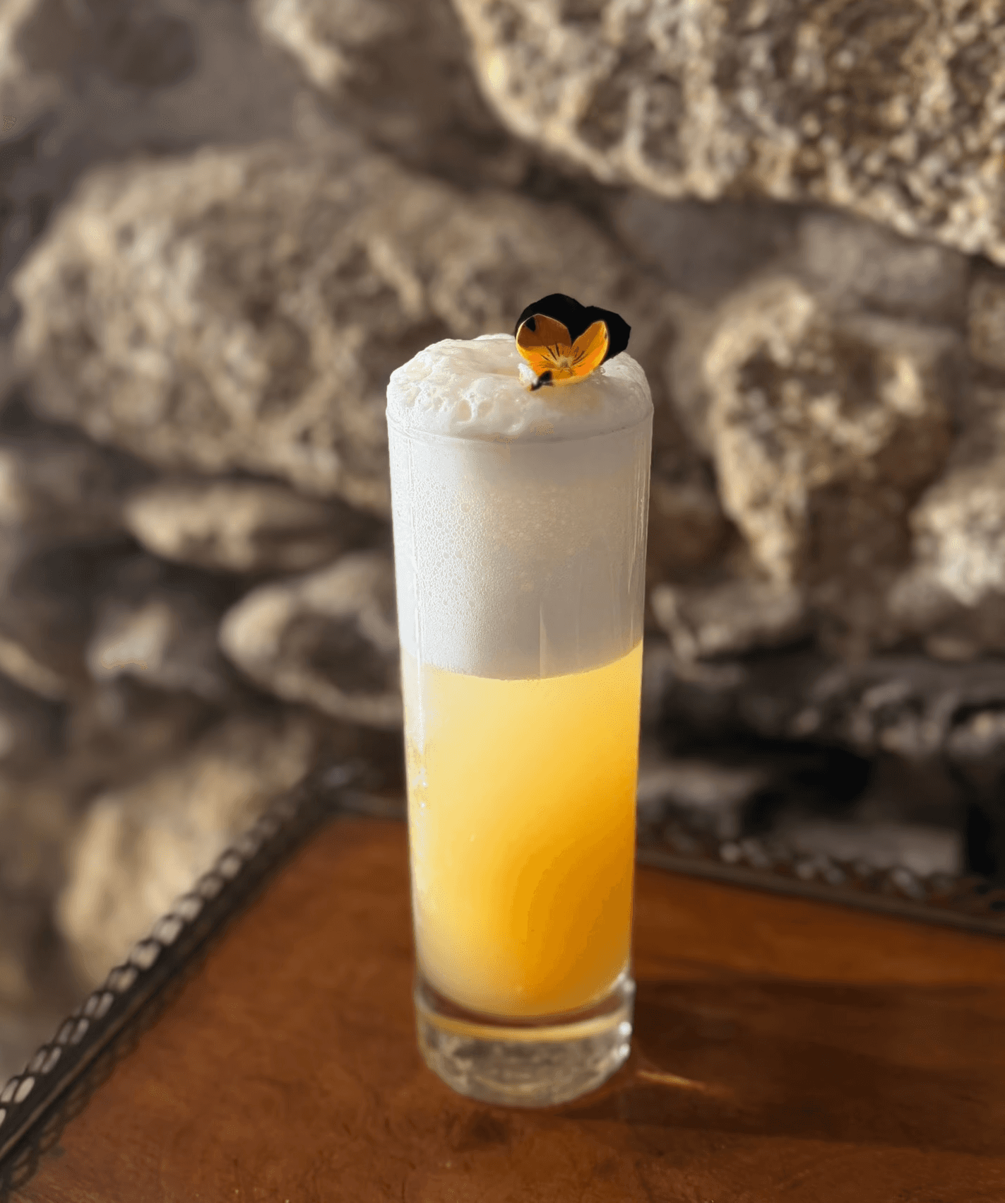 Un cocktail jaune avec une mousse blanche sur un meuble en bois