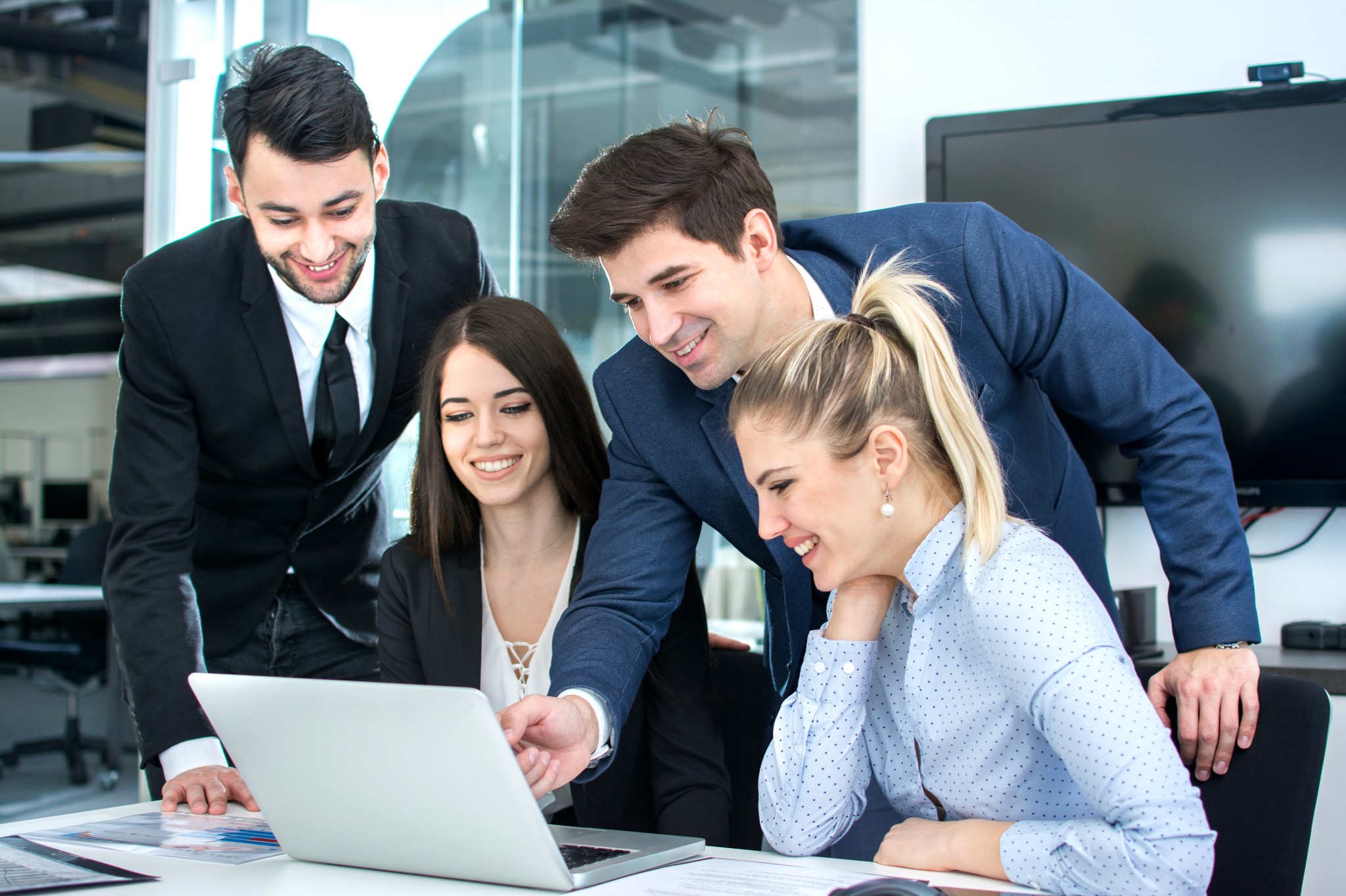 Professionals collaborate on a laptop in office