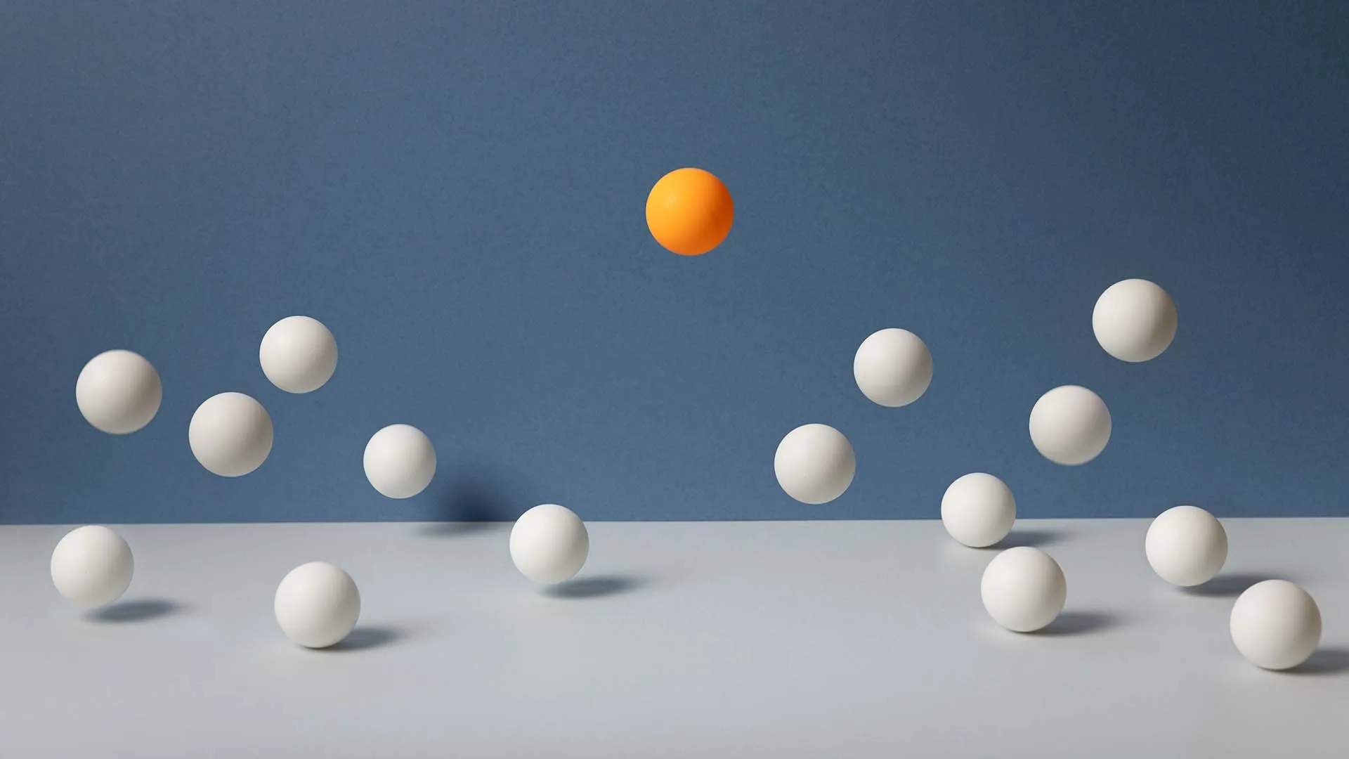 An orange ball bouncing higher than a group of generic white balls