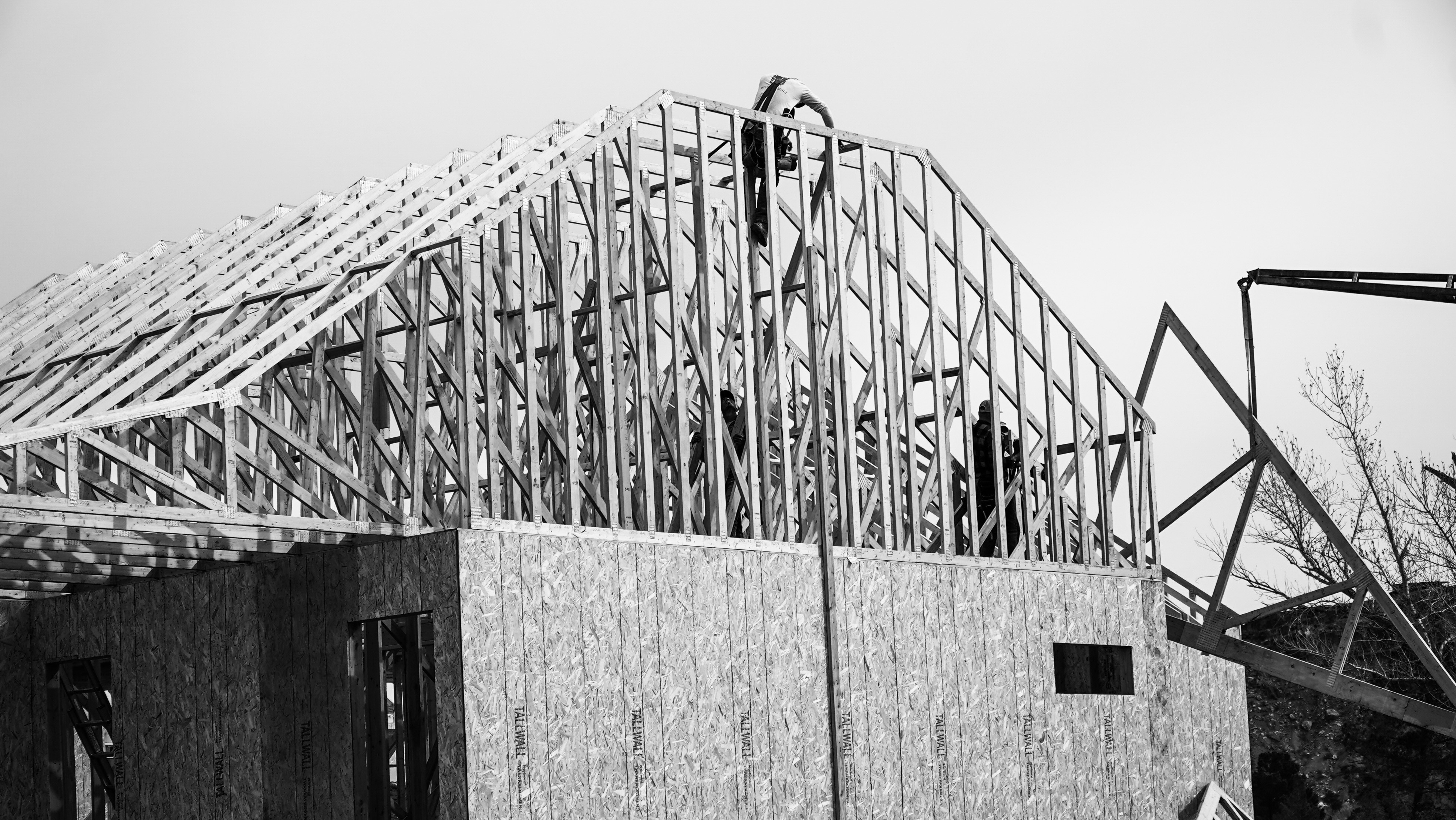 Black and white photo of a framed house with workers putting up trusses in a Southern Utah home.