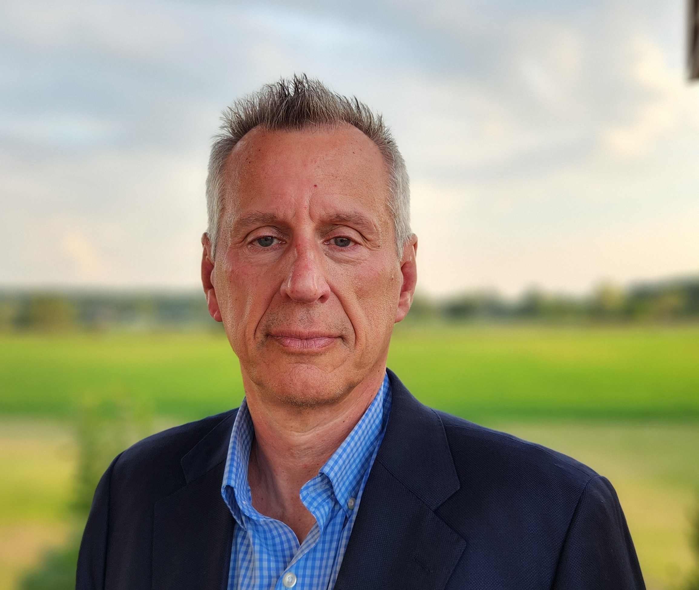 Headshot of Len Middelton as he stands in a green field and looks at the camera 