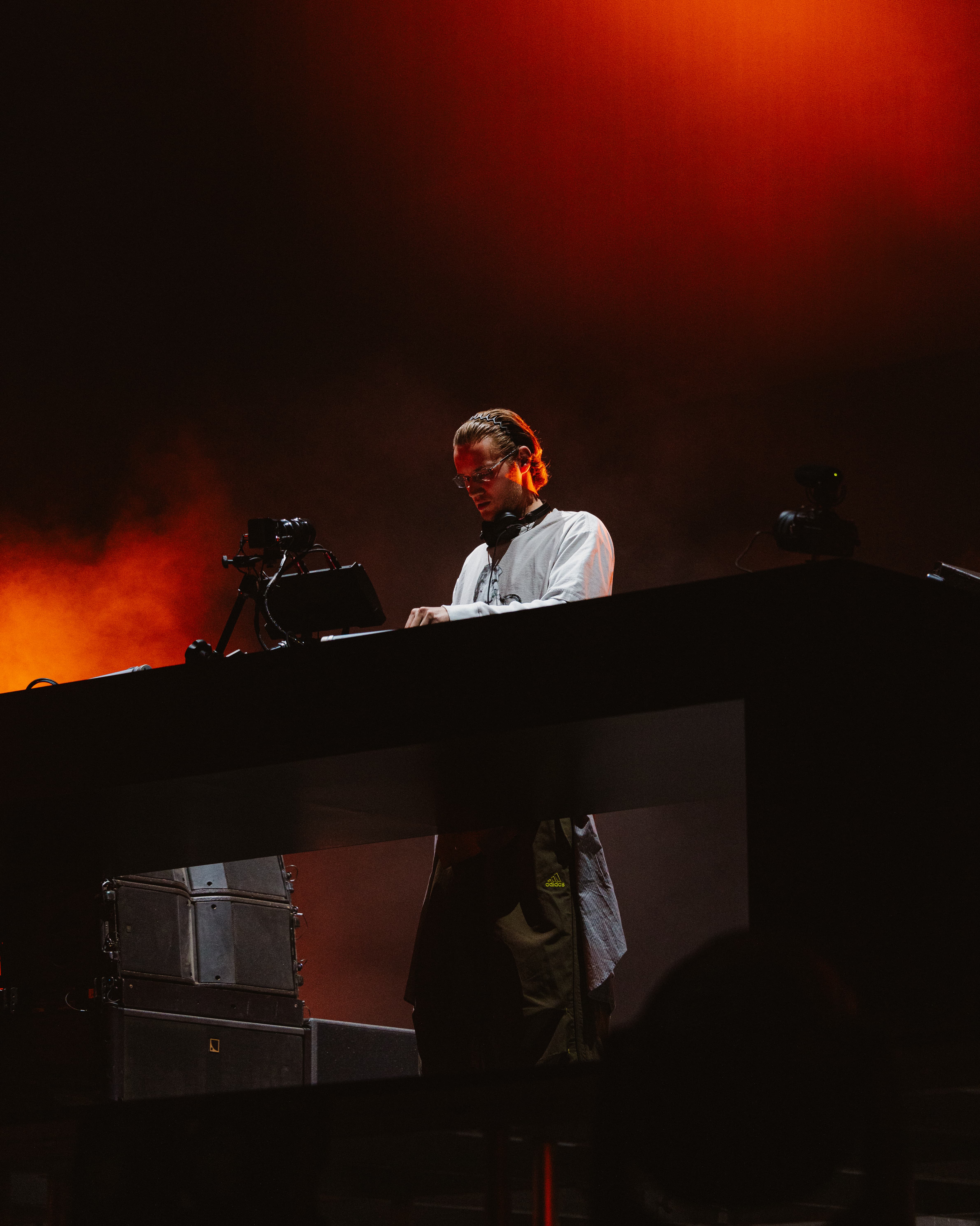 MAU P performing live at Coachella 2025 behind the decks under red stage lighting, captured by A World Away creative director Brandon Densley