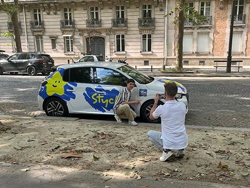 Photo d'un tournage avec une voiture, le fondateur et un acteur