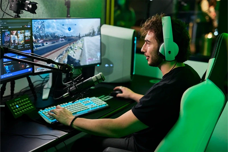 A person wearing headphones sitting in front of a computer playing a video game in the Streamer Pod at Fortress