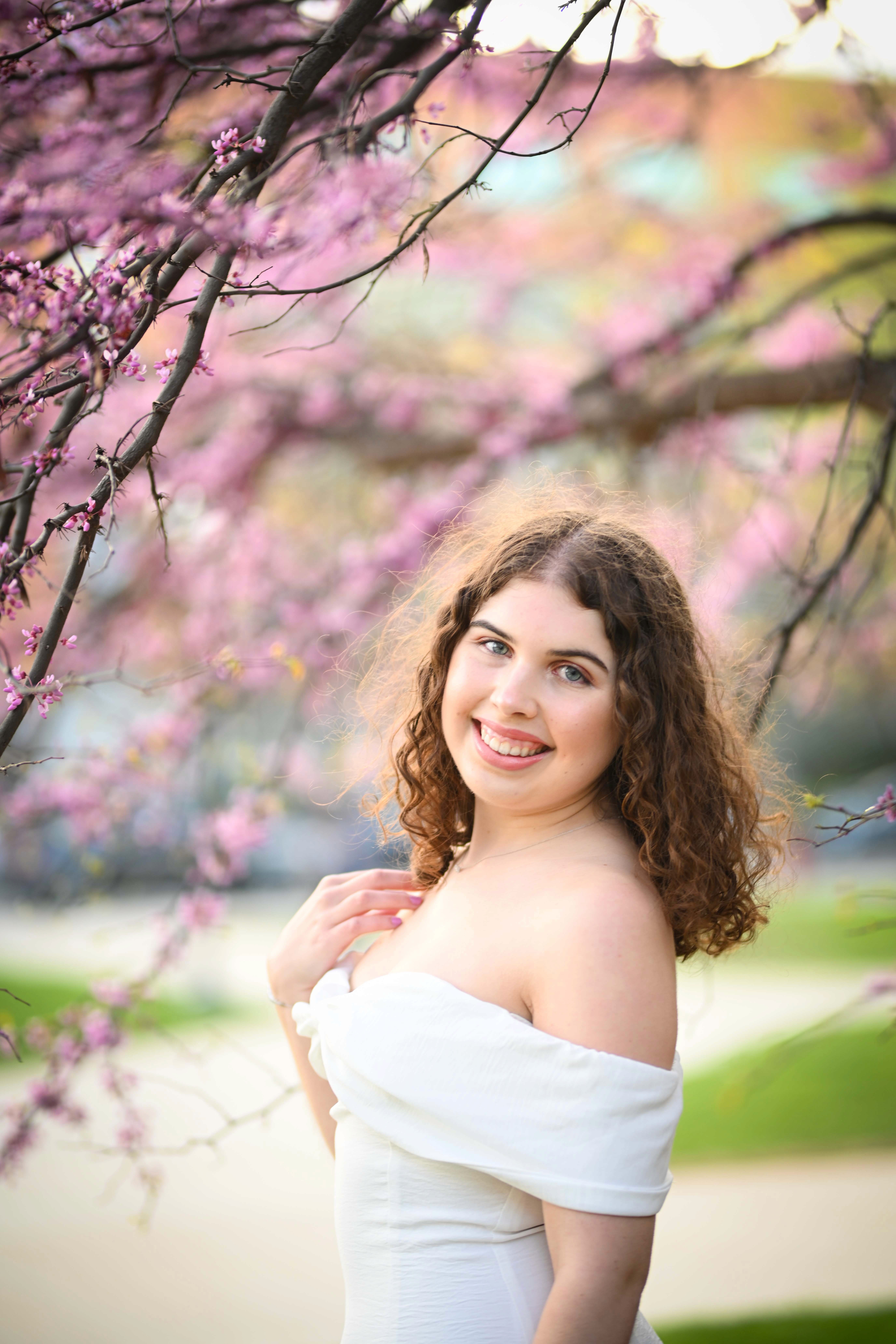 Sarah Penrose smiling at the camera surrounded by a cherry blossom tree