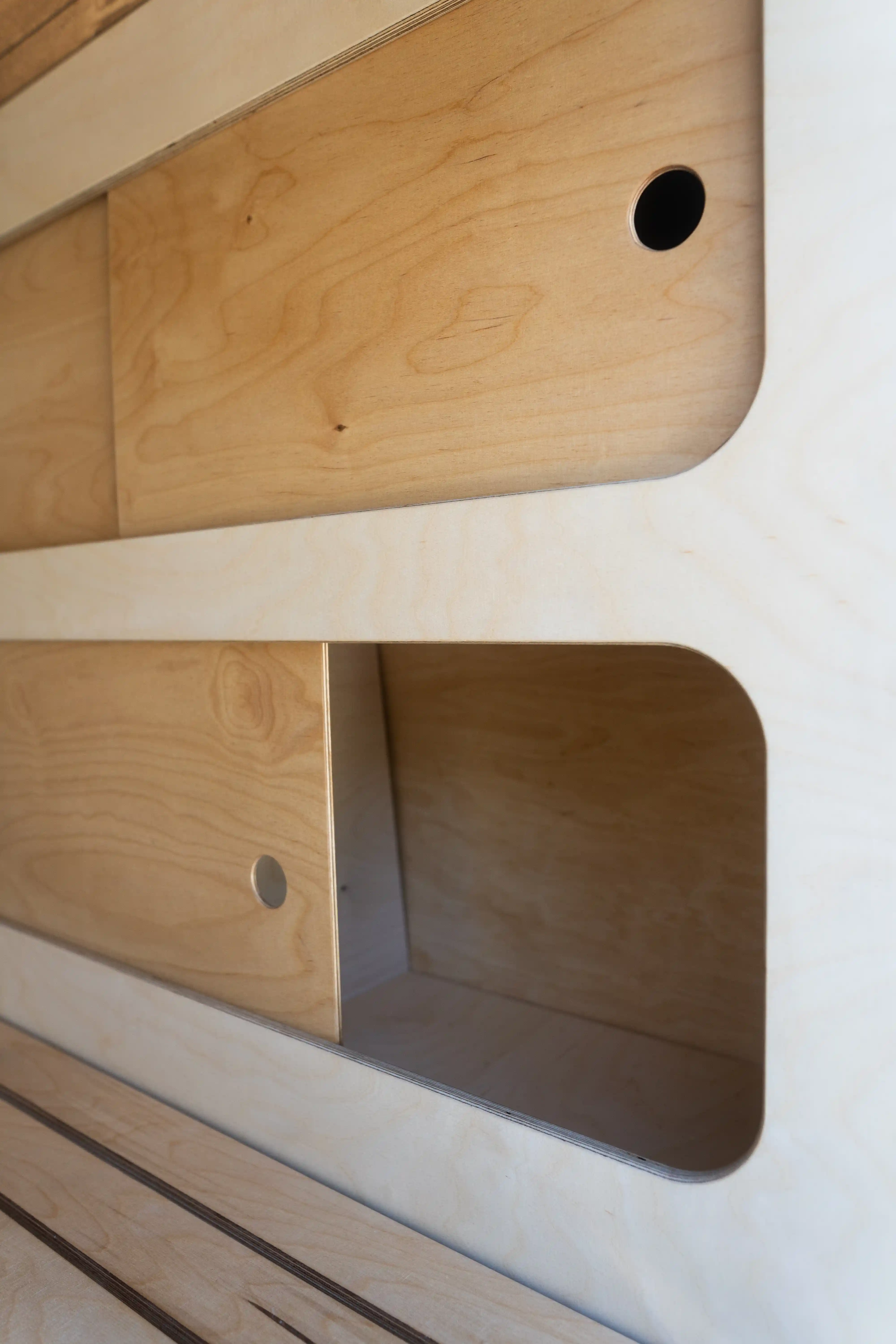 Detailaufnahme der Schiebetüren des Kleiderschranks im Renault Master Camper-Ausbau aus Multiplex, zeigt Verarbeitung und Materialstruktur