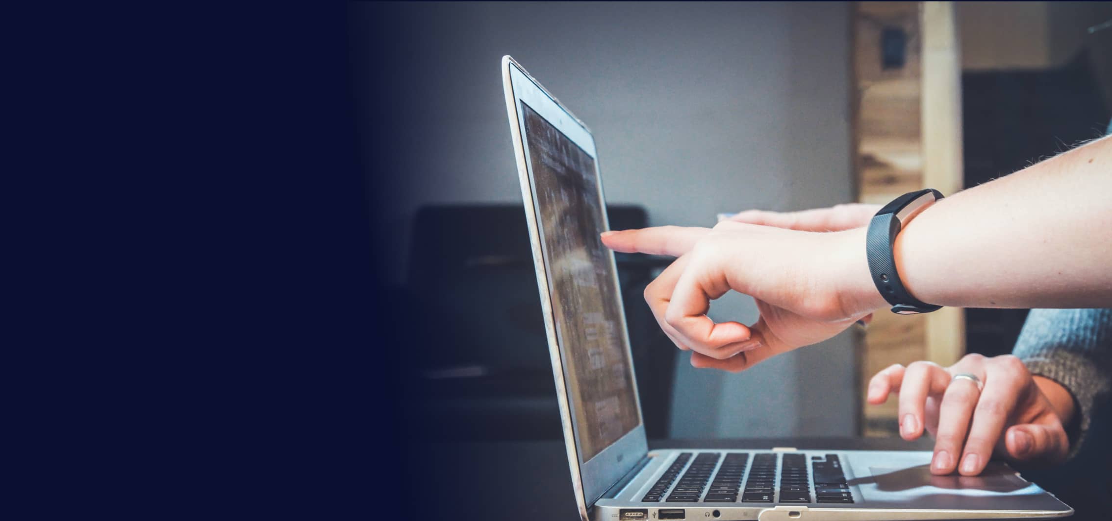 Two people are working on a laptop and pointing at the display.