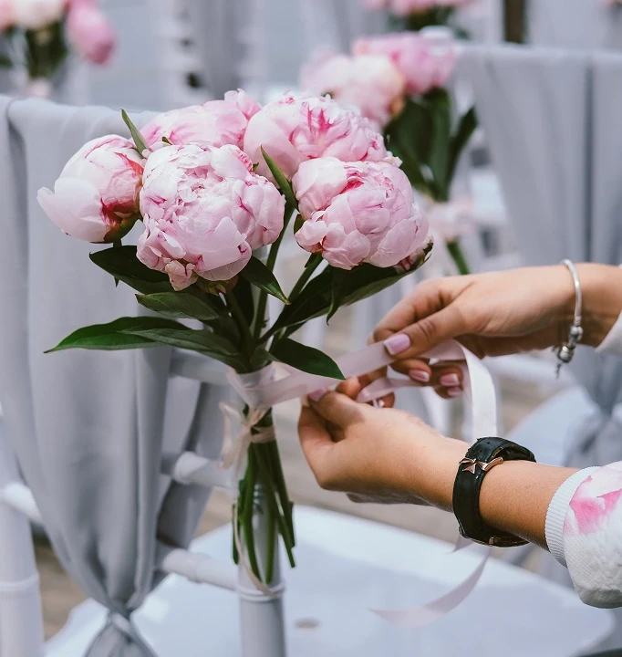 Украшение стула букетом пионов с серой тканью и лентой