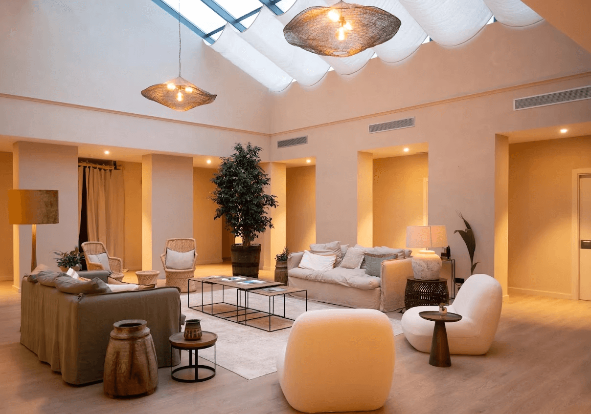 Espace HALO Longevity avec verrière, luminaires, arbre central et salon