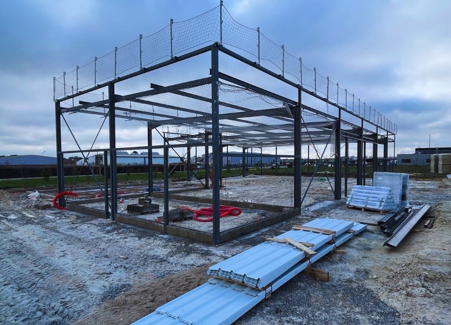 Charpente métallique en cours d’assemblage sur une dalle bétonnée en construction.