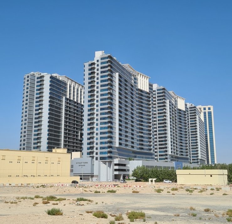 Full view of Skycourt Towers Dubai residential complex under a clear blue sky, managed by expert real estate agents.