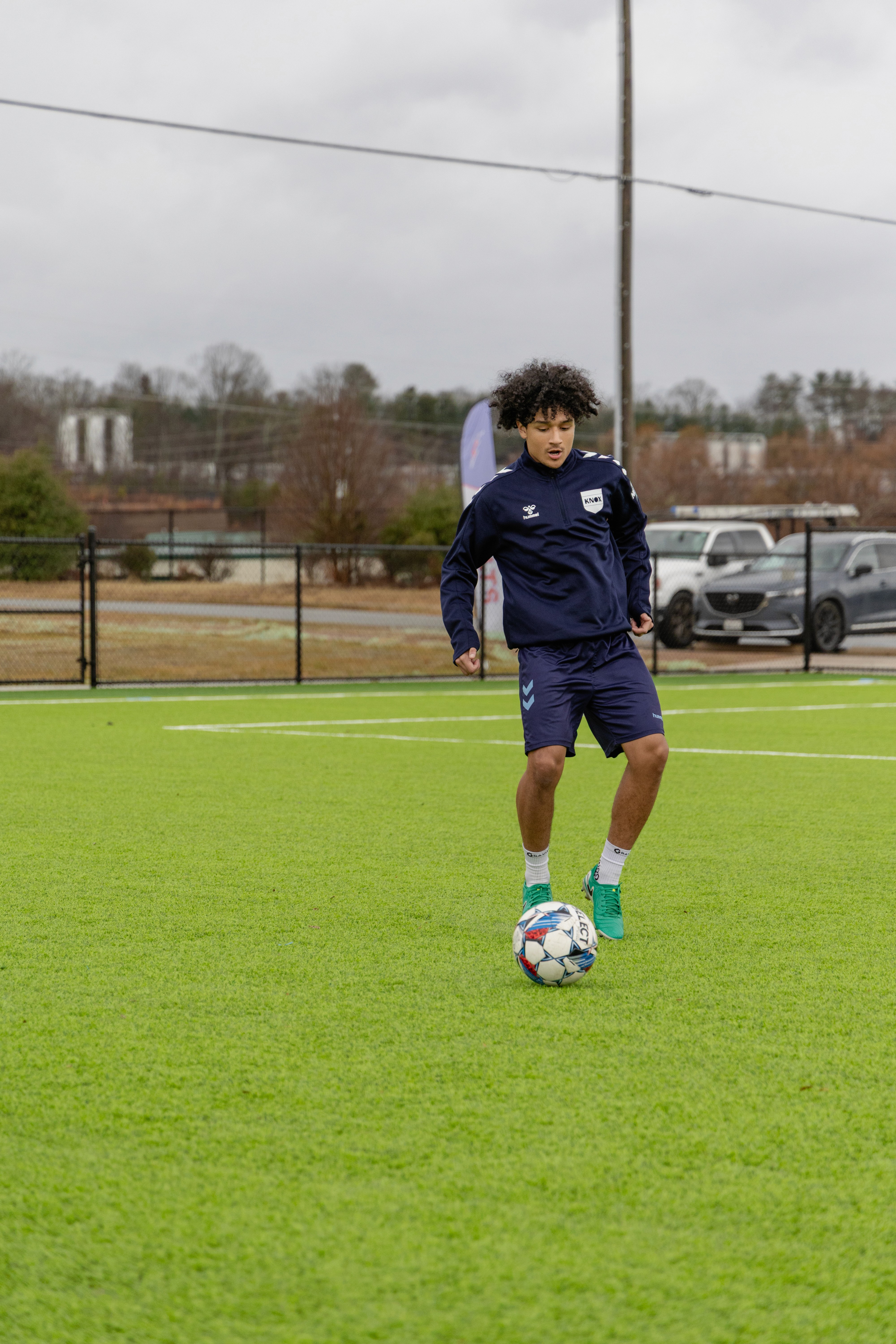 A young person with short, curly hair gazes directly at the camera against a neutral background.