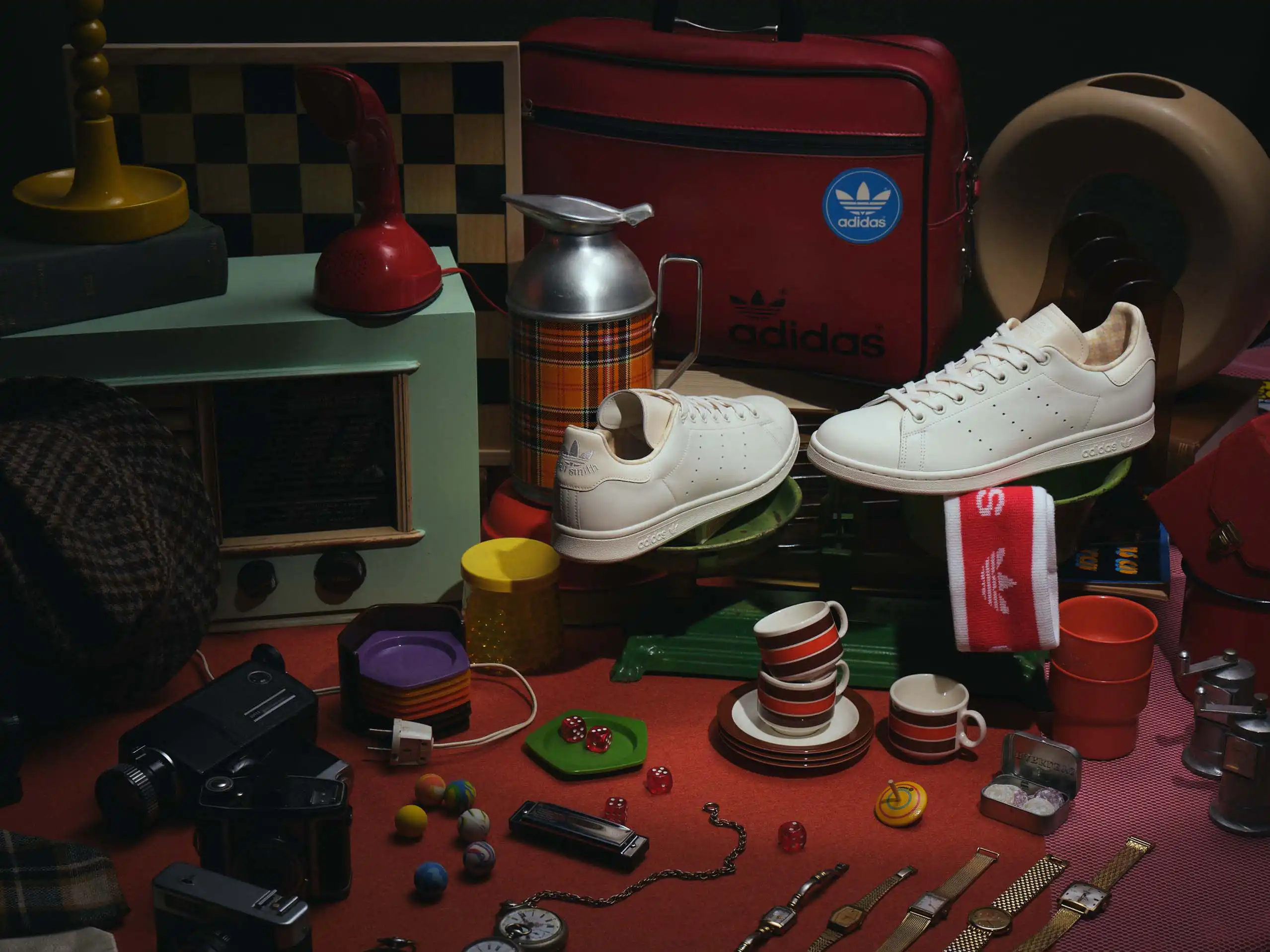 Close-up of a vintage Adidas sneaker sole beside a camera, a chess piece and a small desk lamp.