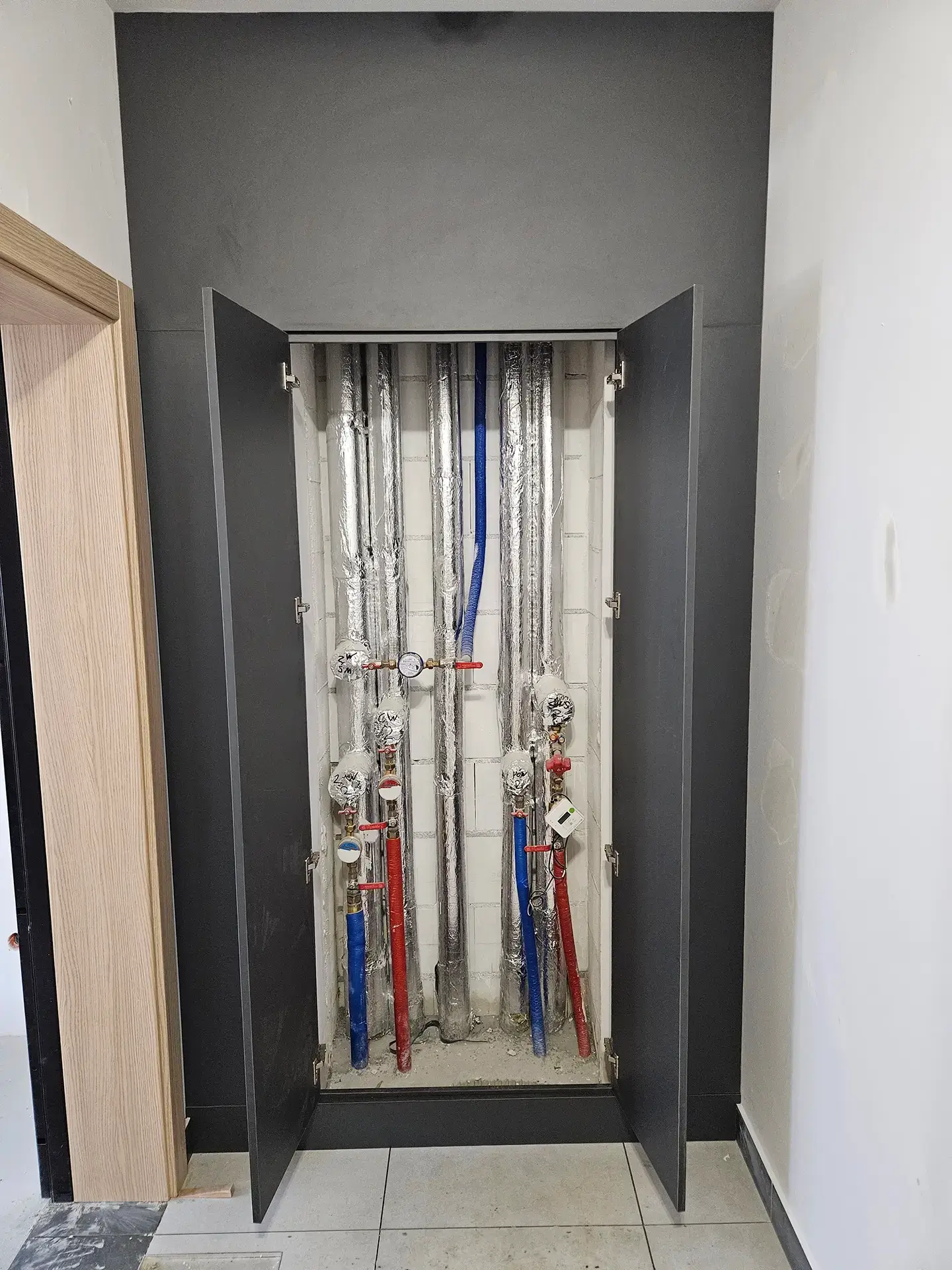 Estetyczna zabudowa techniczna wnęki z rurami i instalacjami w lokalu komercyjnym.