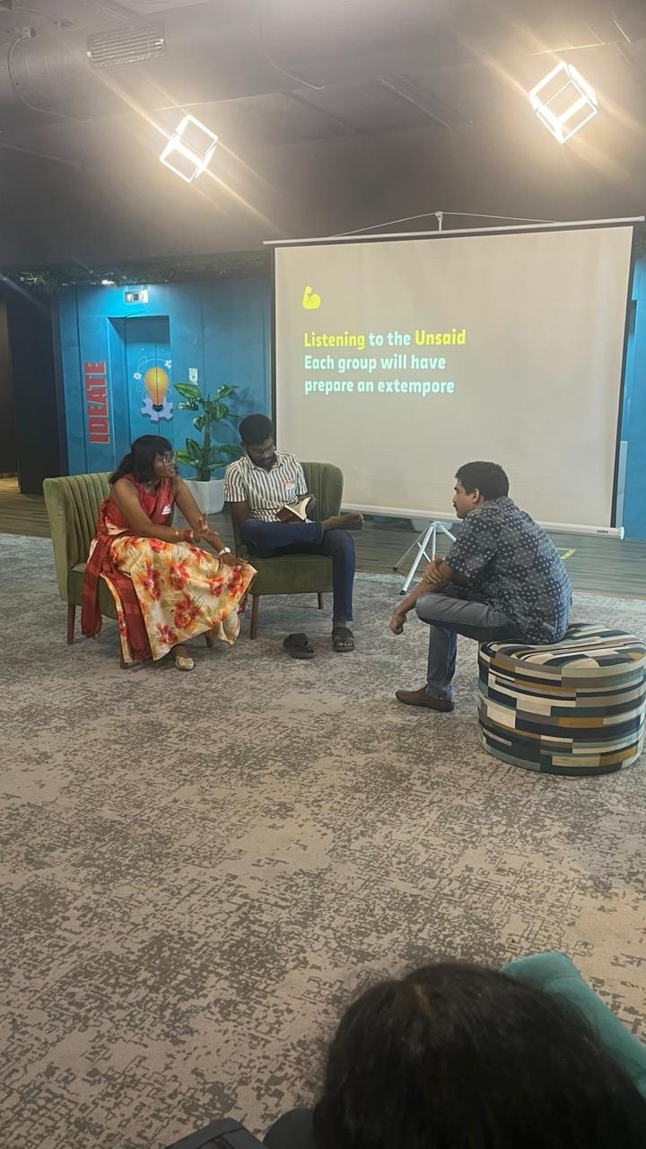 A group of design students seated in a room, with a projector screen displaying information in the background in design day workshop organised by kaphal studio