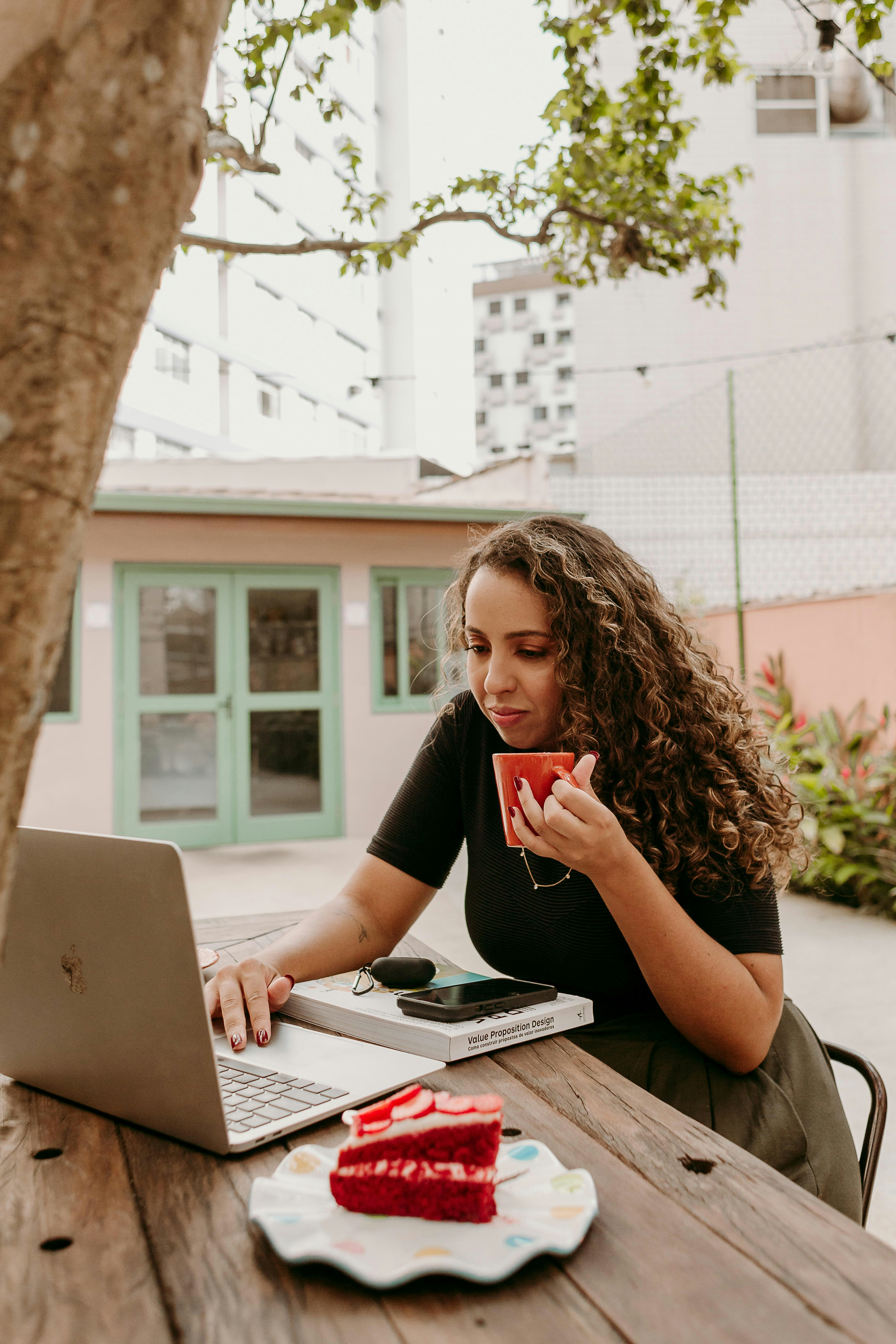 A woman sitting at a table with a laptop and a cup of coffee